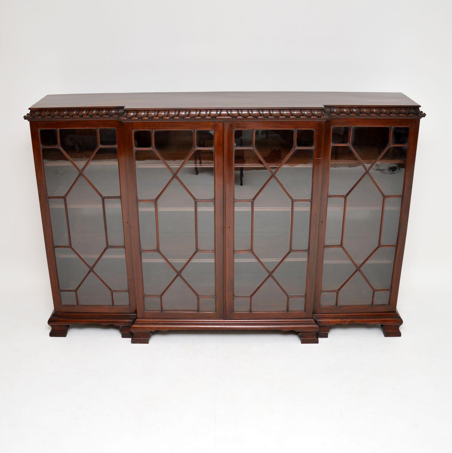 Very strong looking & practicable solid mahogany antique breakfront bookcase in the Chippendale style, dating from around the 1910 period & in excellent condition.

It has a spectacularly scalloped out & carved top edge, which is very distinctive