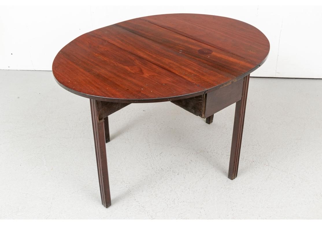 A handsome deep stained mahogany Drop Leaf Table with great form and good wood graining. With straight legs with fluted carving and opening to an Oval suitable for games or tea. 

The Drop Leaf measures  45.5” wide by 34.75” deep by 27.25” high.