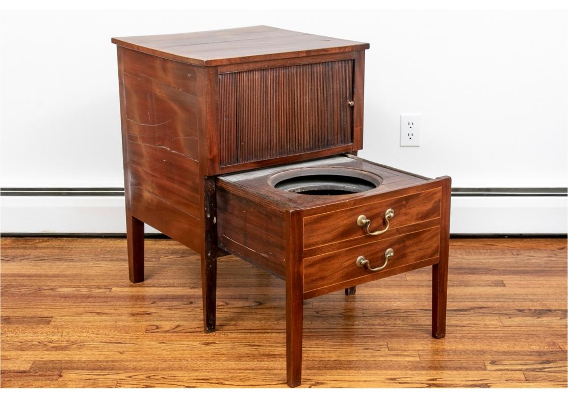Antique mahogany commode stand with tamboured front, circa 1800. When closed, the cabinet appears to have two drawers with string inlay and tamboured doors that conceal storage.
Purchased Mill House Antiques, Connecticut. 
Dimensions: 21