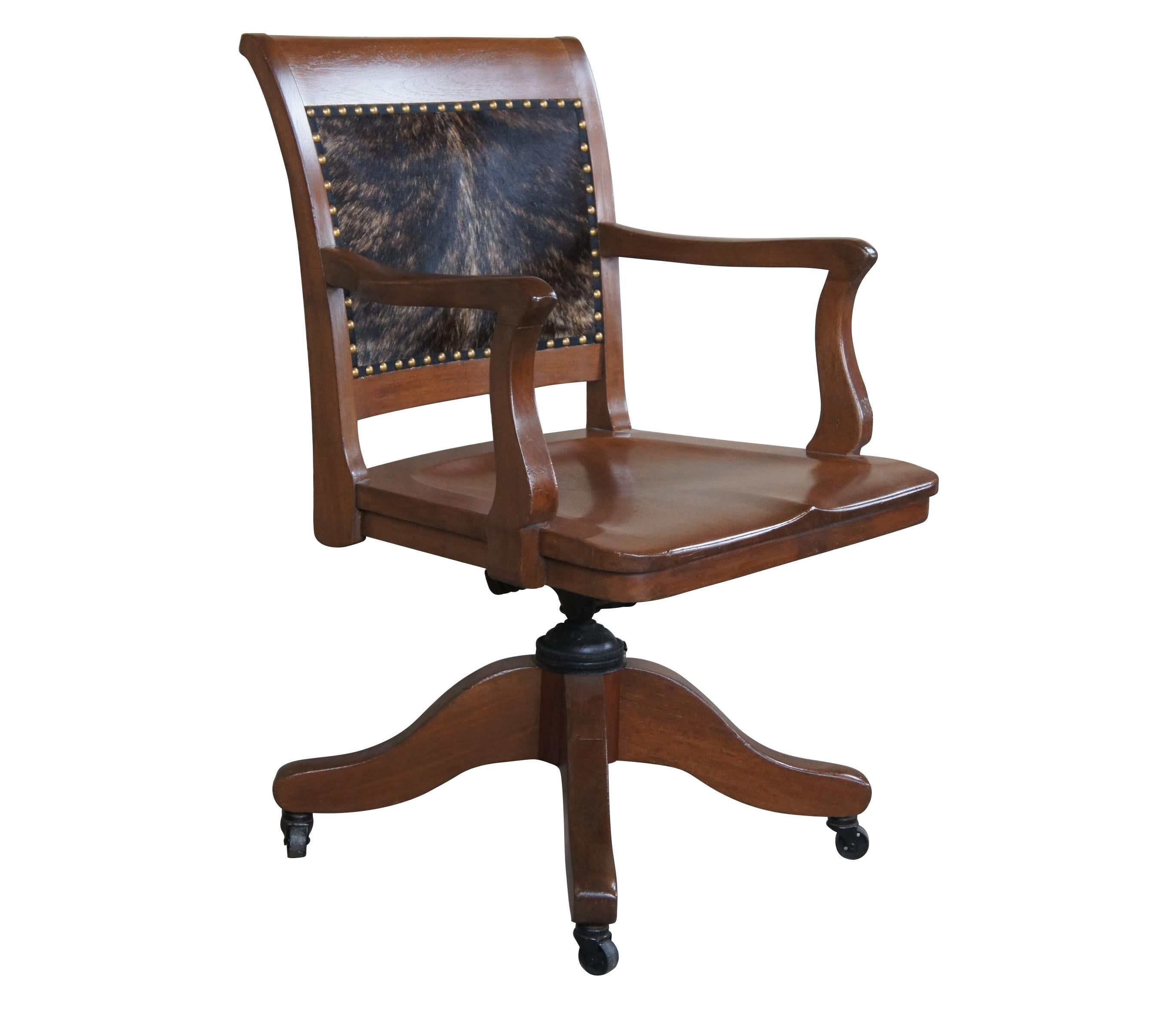 Antique library office desk armchair.  Made of mahogany featuring a rustic / western cowhide and nail head design with swivel base and castors.

Dimensions: 
28