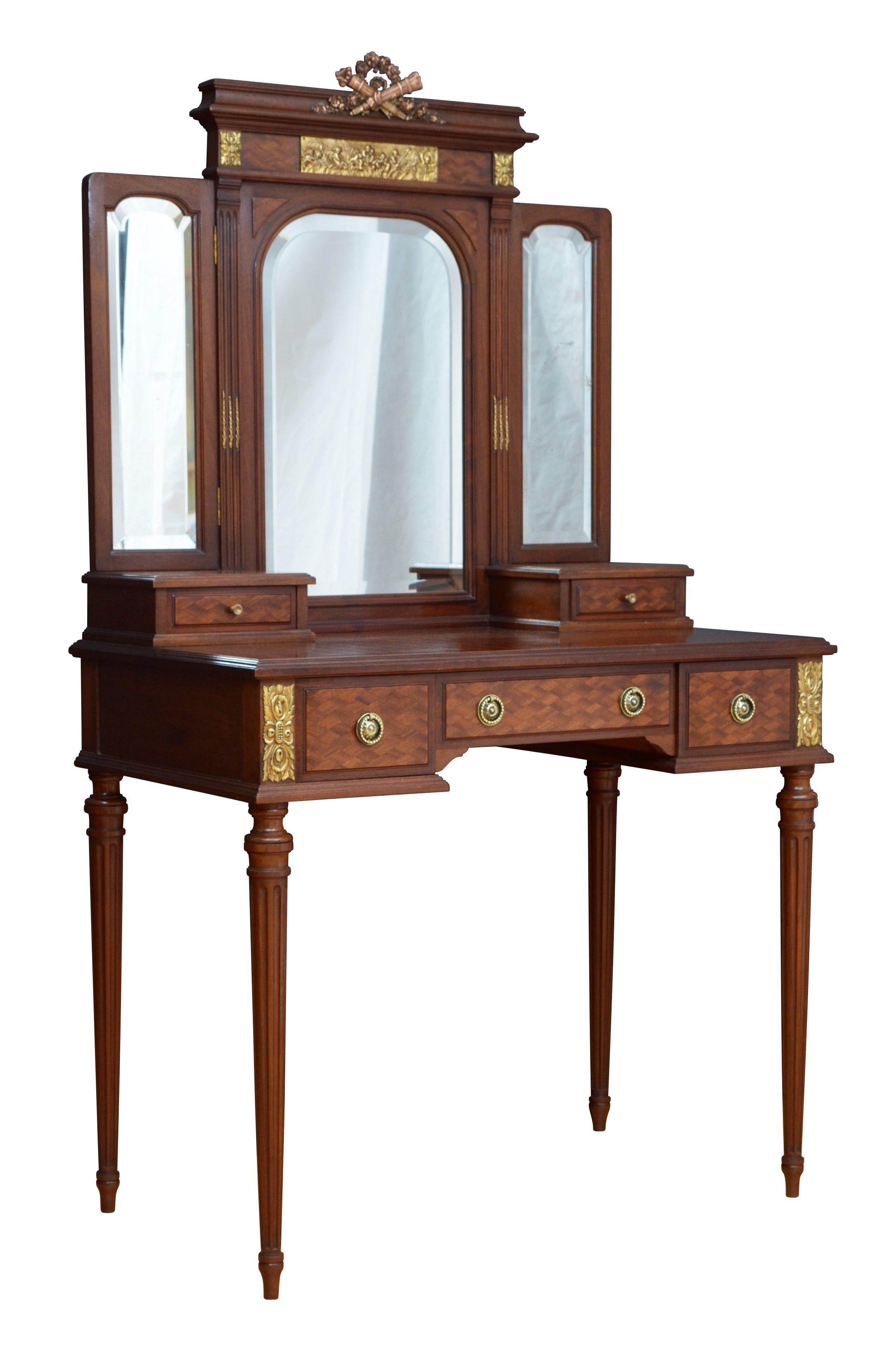 K0 Stylish and very elegant French dressing table in mahogany having shaped triple mirror with original bevelled edge glass (minor imperfections) decorated with a bow to the top above parquetry inlaid top with moulded edge and three frieze drawers
