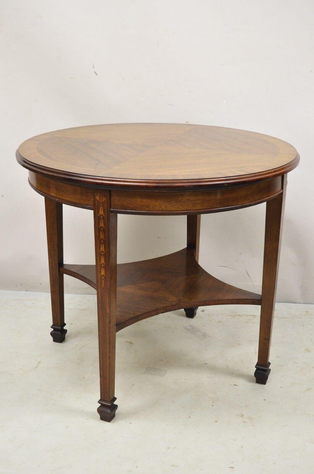 Antique mahogany Edwardian bellflower inlay round center table. Item features a sunburst inlaid top, bellflower inlay to legs, lower shelf, beautiful wood grain, very nice antique item. circa Early 20th century. Measurements: 28.5