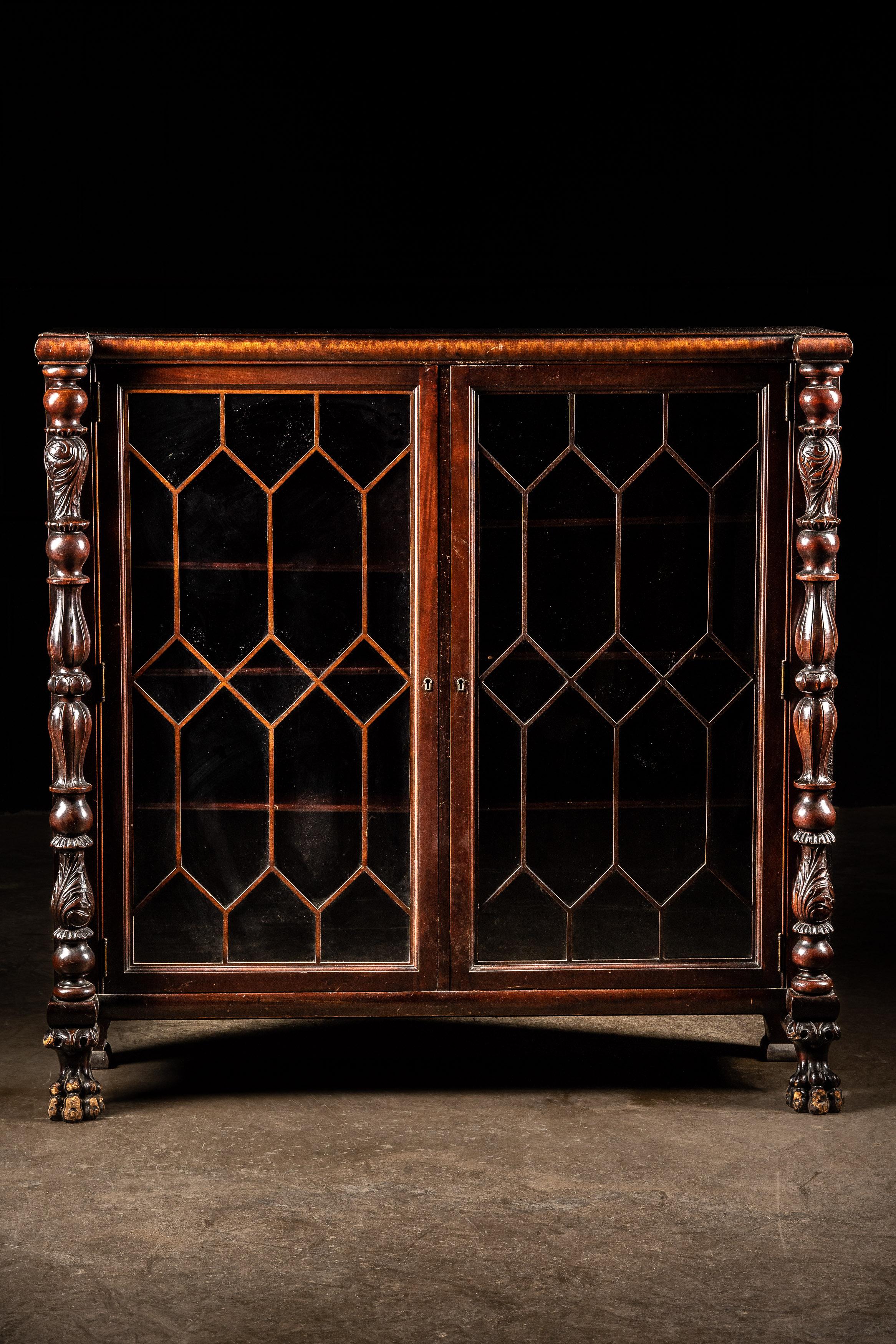 This antique bookcase features construction that appears to be from the American Empire Revival era on the late 19th century. The wood is likely mahogany veneer. The shelves can be moved up or down as necessary. This bookcase has overall dimensions