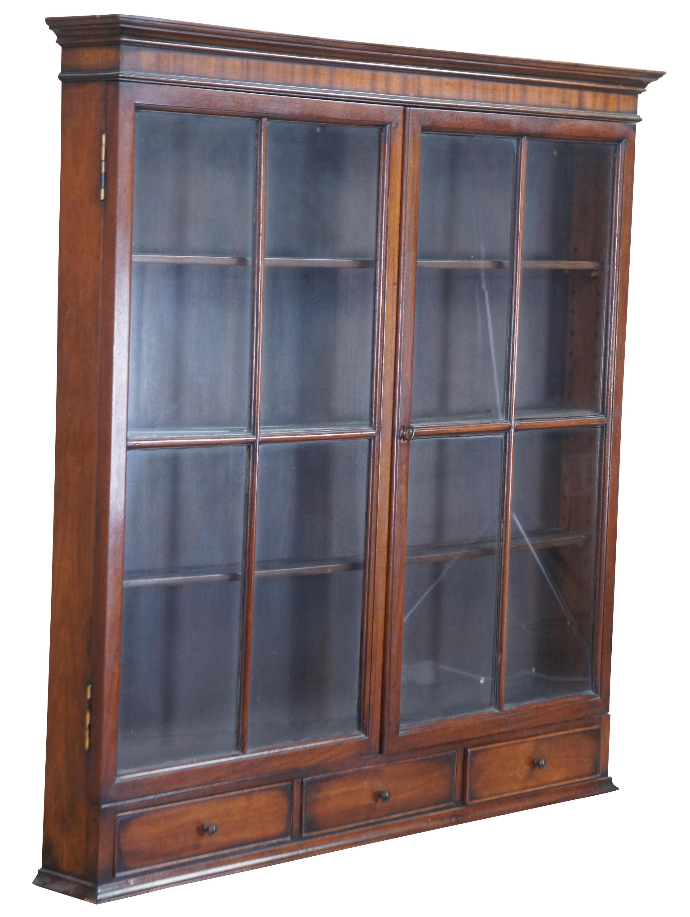 Petite wall curio or display cabinet in the manner of Georgian styling, Circa mid 20th century. Made of mahogany featuring three interior adjustable wood shelves, paned glass doors, and three lower drawers.
   