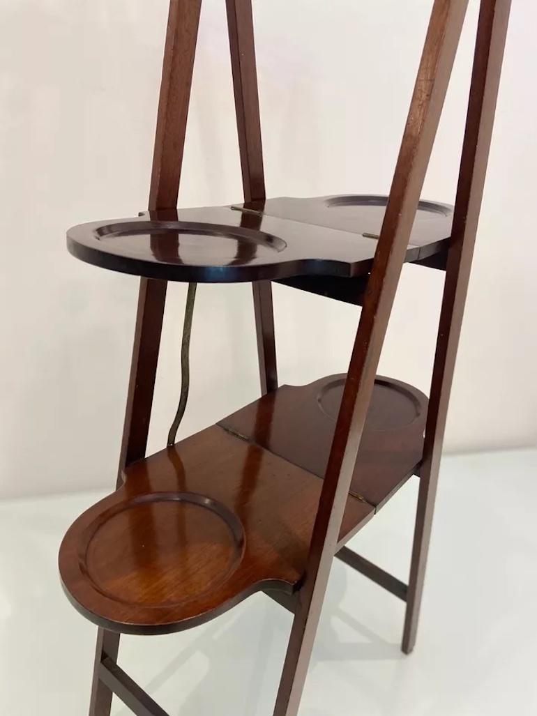 Dieser antike edwardianische Klappständer aus Mahagoni des frühen 20. Jahrhunderts ist ein schönes Beispiel für ein praktisches und einzigartiges Design. 

Der Ständer lässt sich leicht zusammenklappen und ist somit ideal für die platzsparende