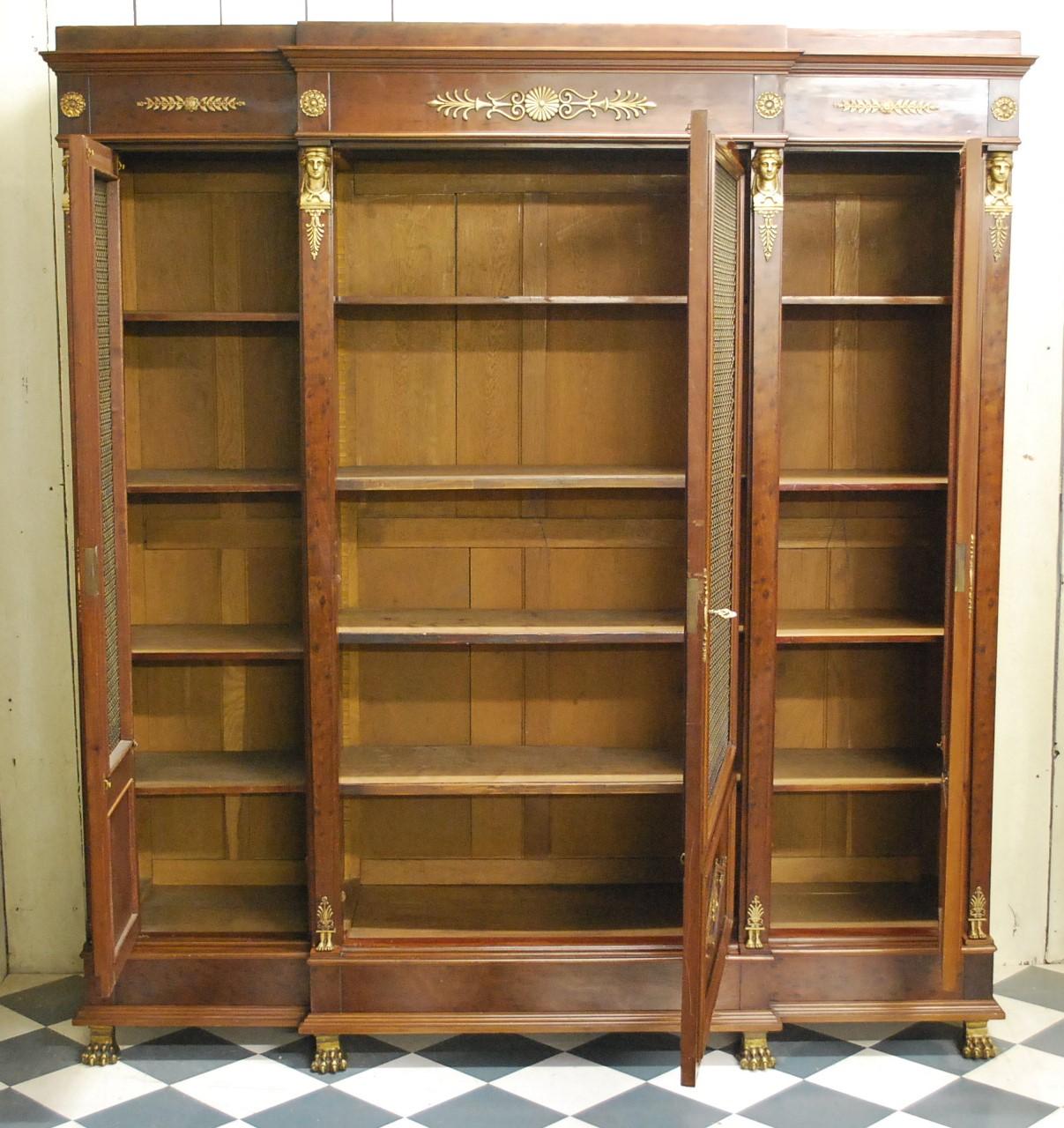 Superb quality French Empire period plum pudding mahogany breakfront bookcase. Standing on gilt paw feet and embellished in classical Egyptian style mounts. Caryatids at the tops of columns with leaves and rosettes on the cornice. The doors are also