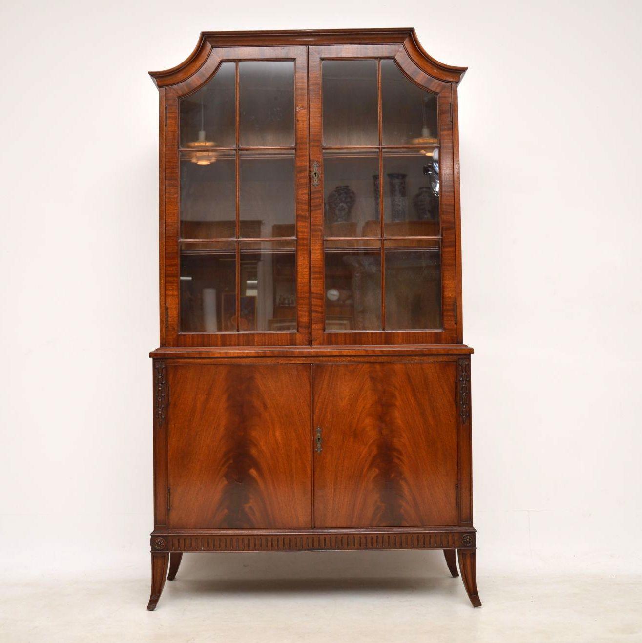 Antique mahogany bookcase on cupboard in good condition and of excellent quality. It has a nice elegant design, with curved top corners and sabre legs. The top section has astral glazed doors, with adjustable shelves inside and a polished back. The