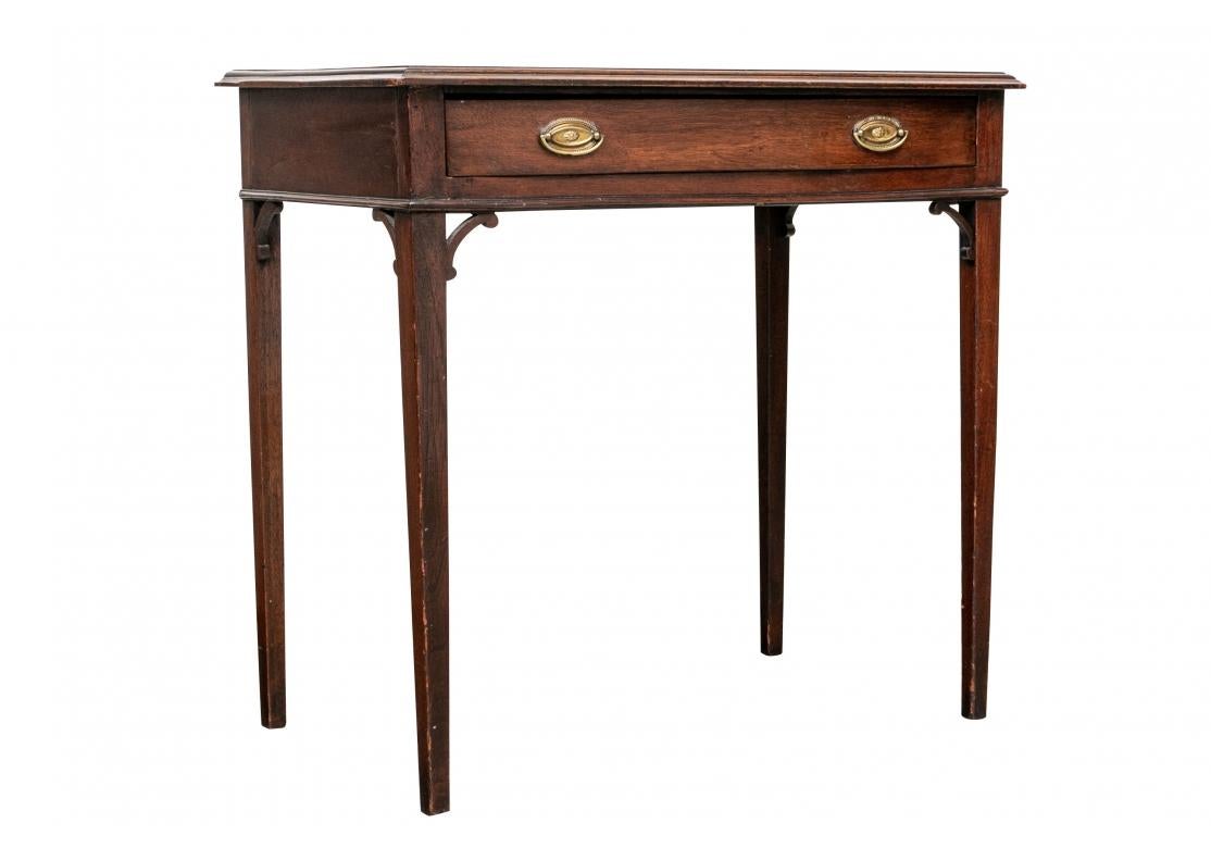 A classic style, the top with a carved edge and a long apron drawer. The fine oval brass bales beaded with rosette centers. Raised on square tapering legs with front and back spandrels.
 
The Table measures L. 28 1/2