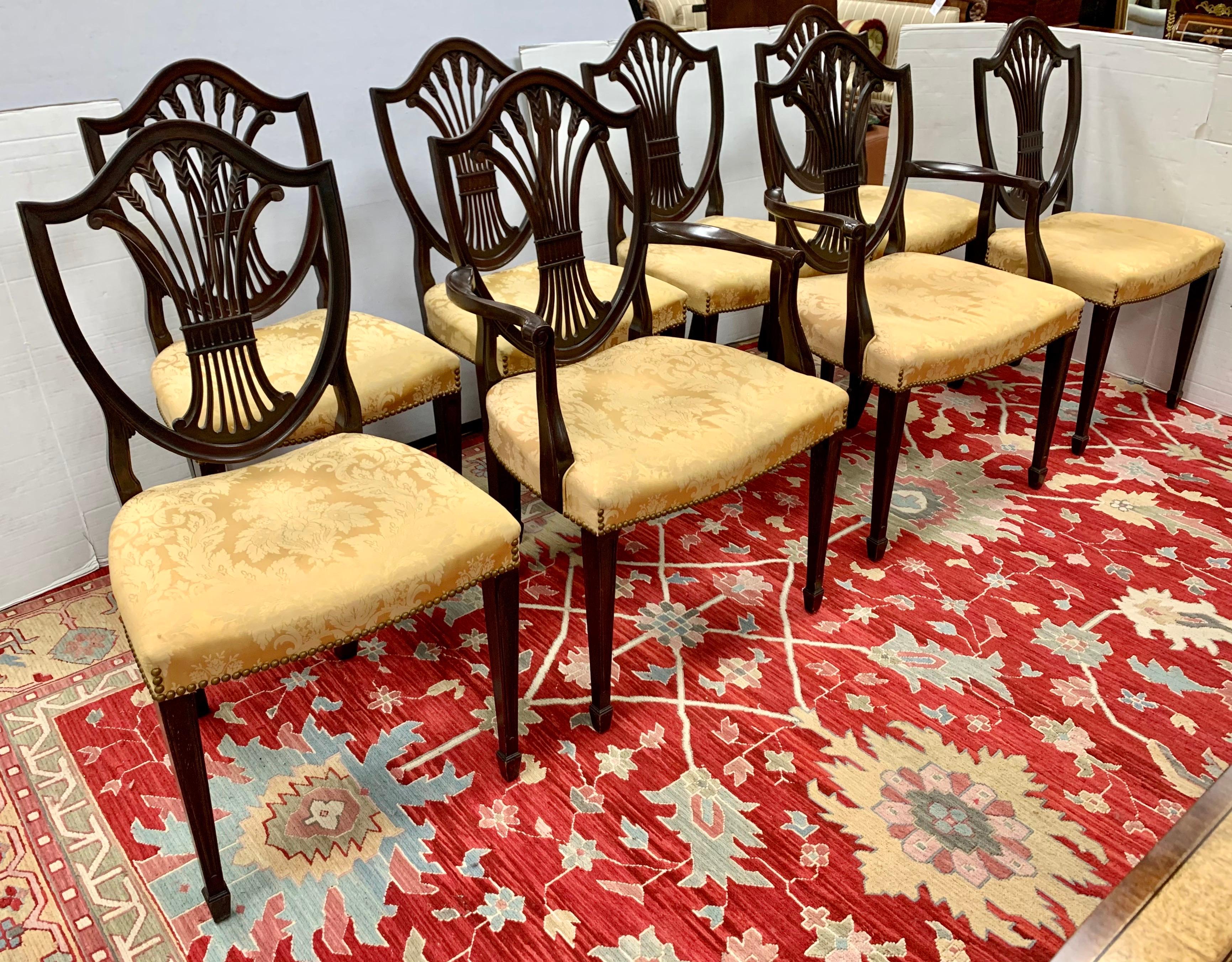 Fine set of antique carved mahogany Hepplewhite dining chairs circa, 1900 consisting of two arm chairs and six side chairs all with striking shield shaped backs and decorative pierced back splats with a wheat sheaf design. They are upholstered in a