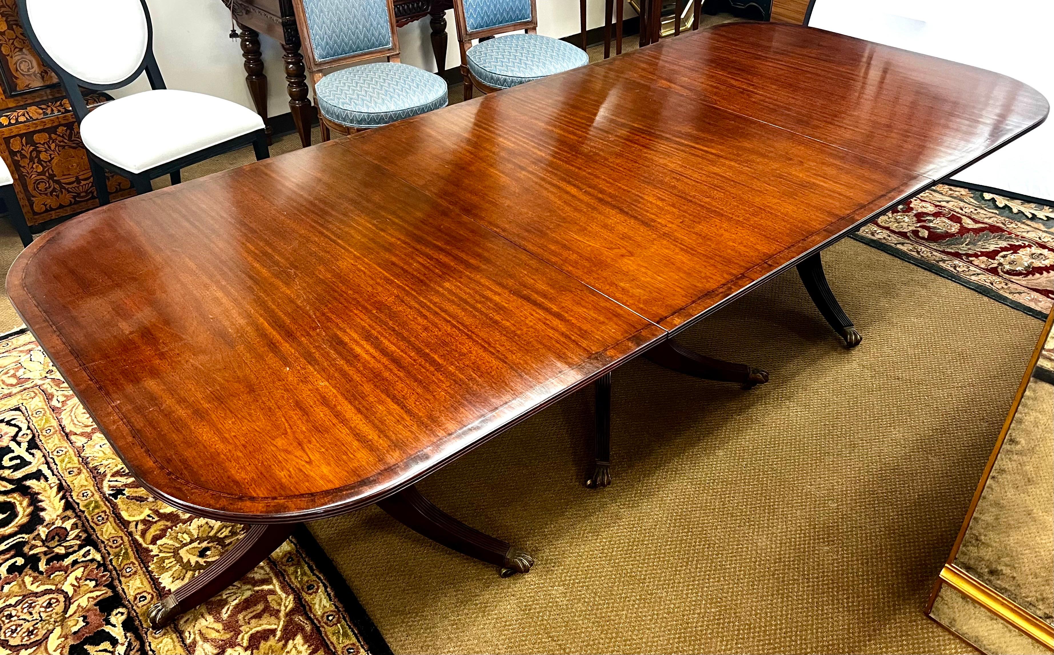 Magnificent turn of the century bench-made triple pedestal Duncan Phyfe style dining table in very good condition. Rare to fund one in such good condition given its age. Features reeded saber legs with brass toe caps and castors, banded edge to top.