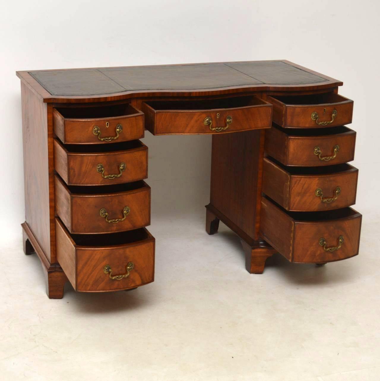 This antique mahogany serpentine fronted desk has small proportions, but still has a generous sized kneehole space. It’s flame mahogany all over and is finished off just as nicely on the back. The leather writing surface is hand colored and tooled