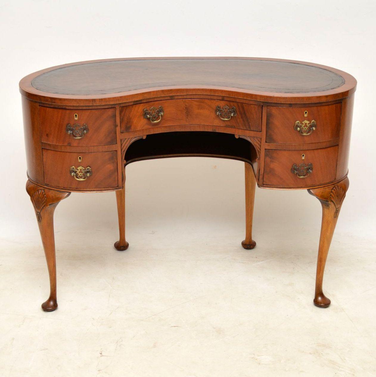 Small antique kidney shaped flame mahogany desk in good condition dating from the 1920s period. It has a tooled leather writing surface and the flame mahogany drawers have original brass handles and locks. There's also an open storage compartment