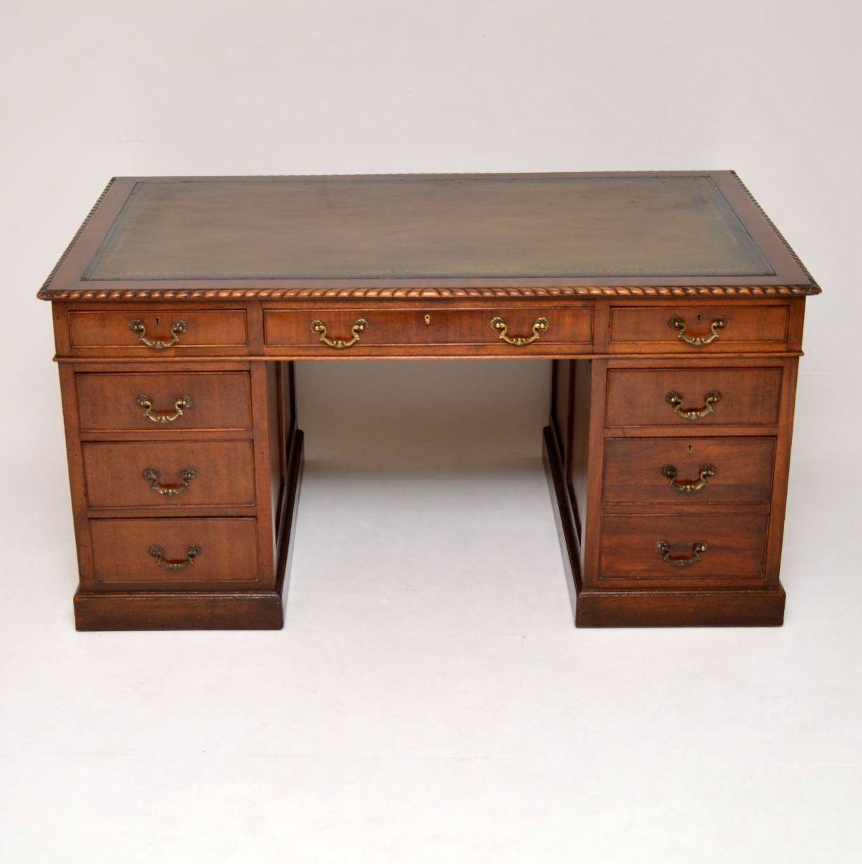 Large antique mahogany pedestal desk dating from circa 1920s period & in excellent condition. It has a hand colored tooled leather writing surface & a gadrooned edge. This is a well constructed & functional piece of furniture, with panelled sides &