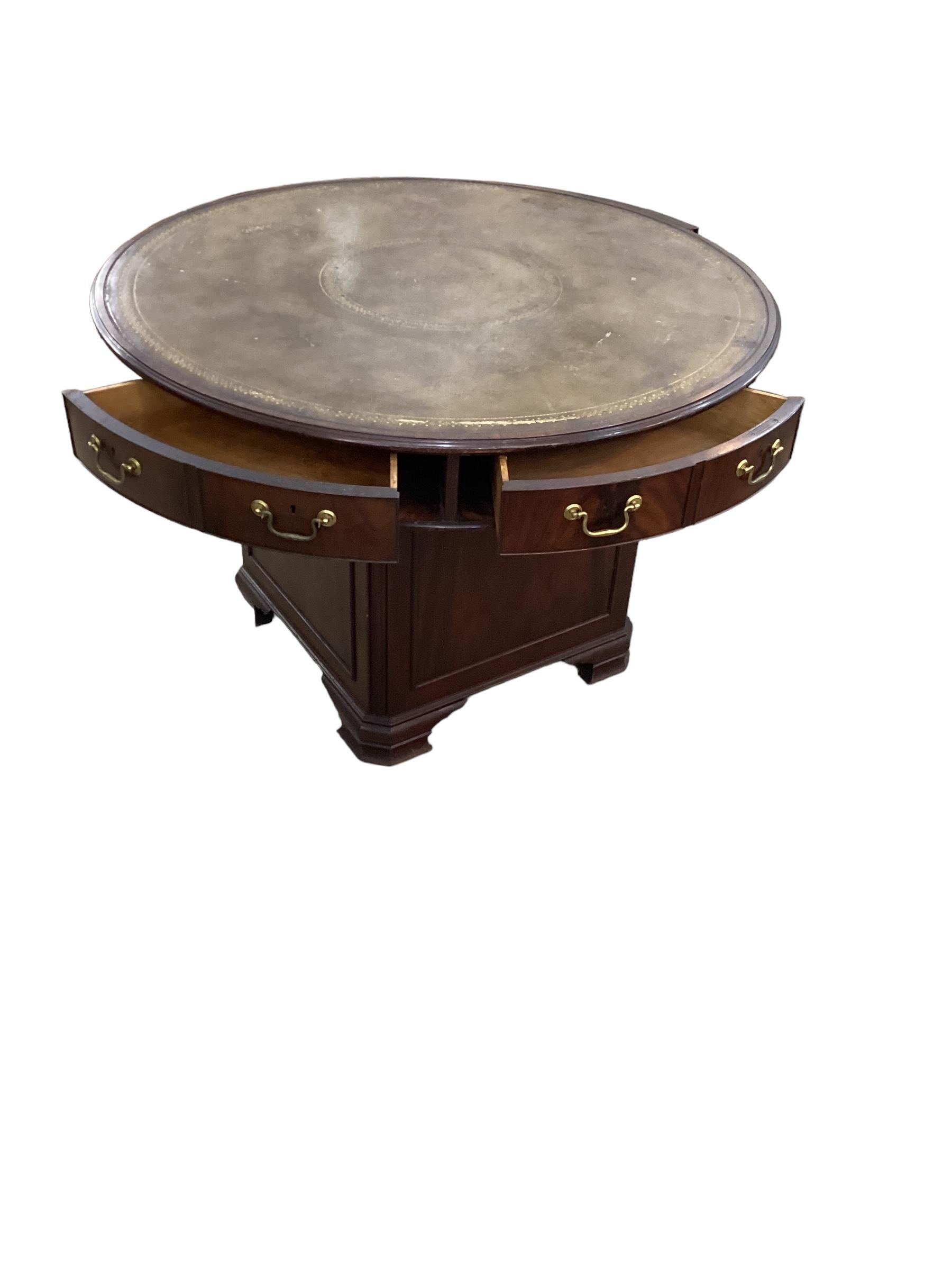 Antique Mahogany Leather Top Rent Drum Table. The to fitted with six wedge shaped drawers. The base has a storage compartment that has a lock to keep valuable safe and each drawer also has a functional lock. Flame mahogany construction with brass