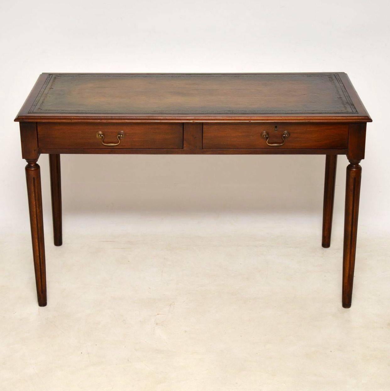 Nice quality antique mahogany writing table desk in lovely condition. It has a tooled leather writing surface, with two drawers below that have the original brass handles. One of the drawers has a lock. This desk sits on turned fluted legs and it
