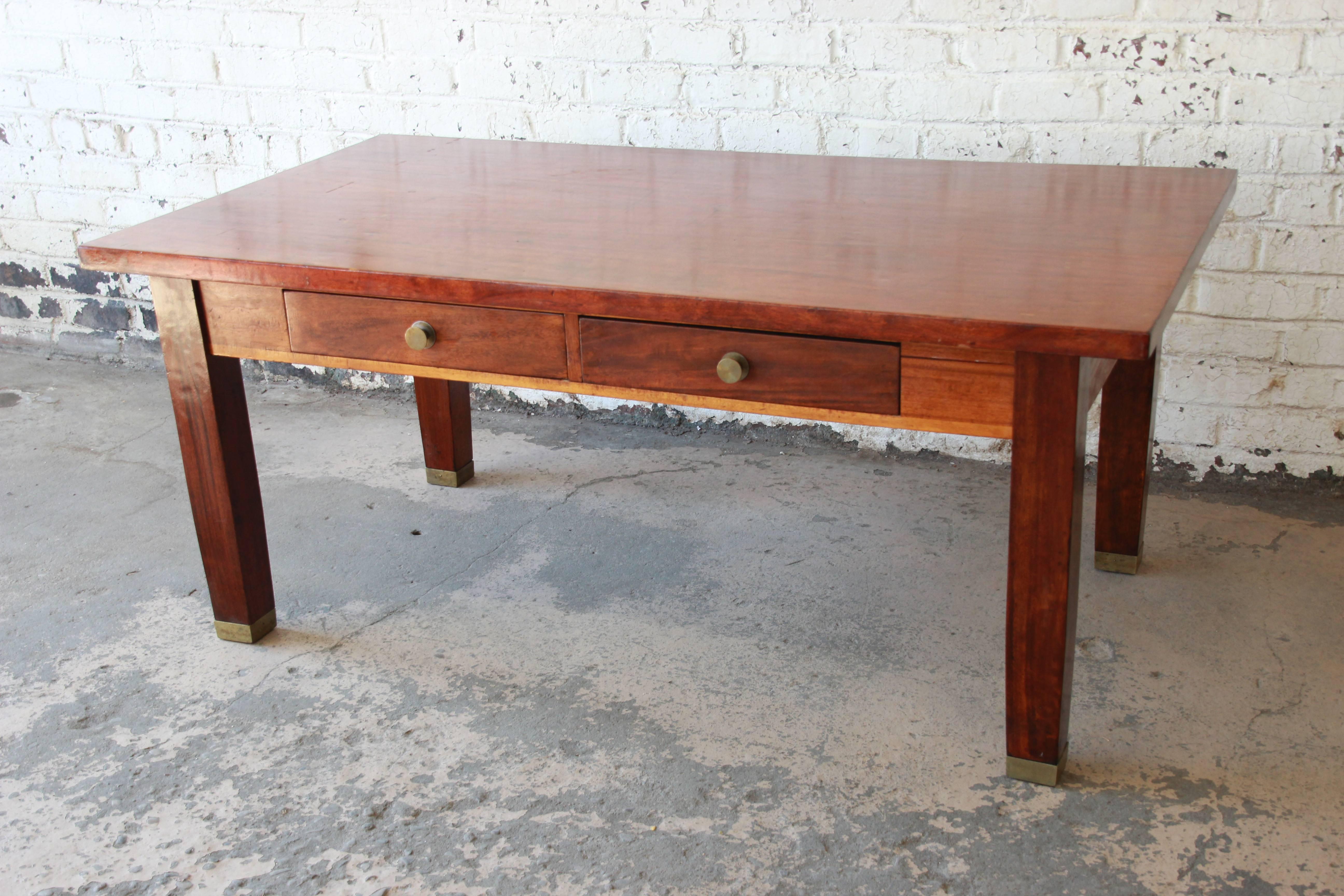 A beautiful antique mahogany library table. The table was made circa 1900 and features gorgeous mahogany wood grain and solid mahogany brass-tipped legs. It offers good storage, with two dovetailed drawers. Brass hardware is original. The table is