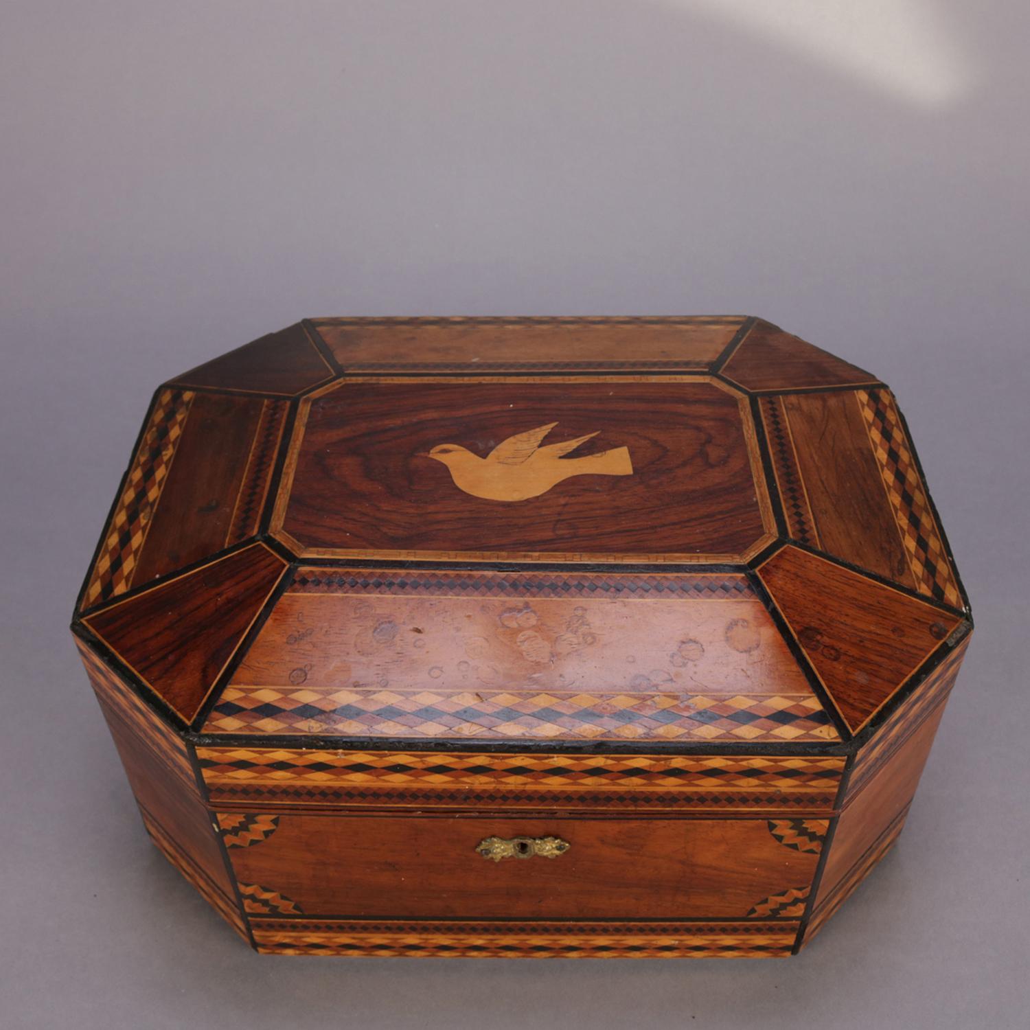 An antique mahogany marquetry jewelry box features clipped corner form with faceted lid having central satinwood inlaid dove with repeating diamond bordering with sunburst corbelles, velvet lined interior with bevelled mirror and tray, 19th