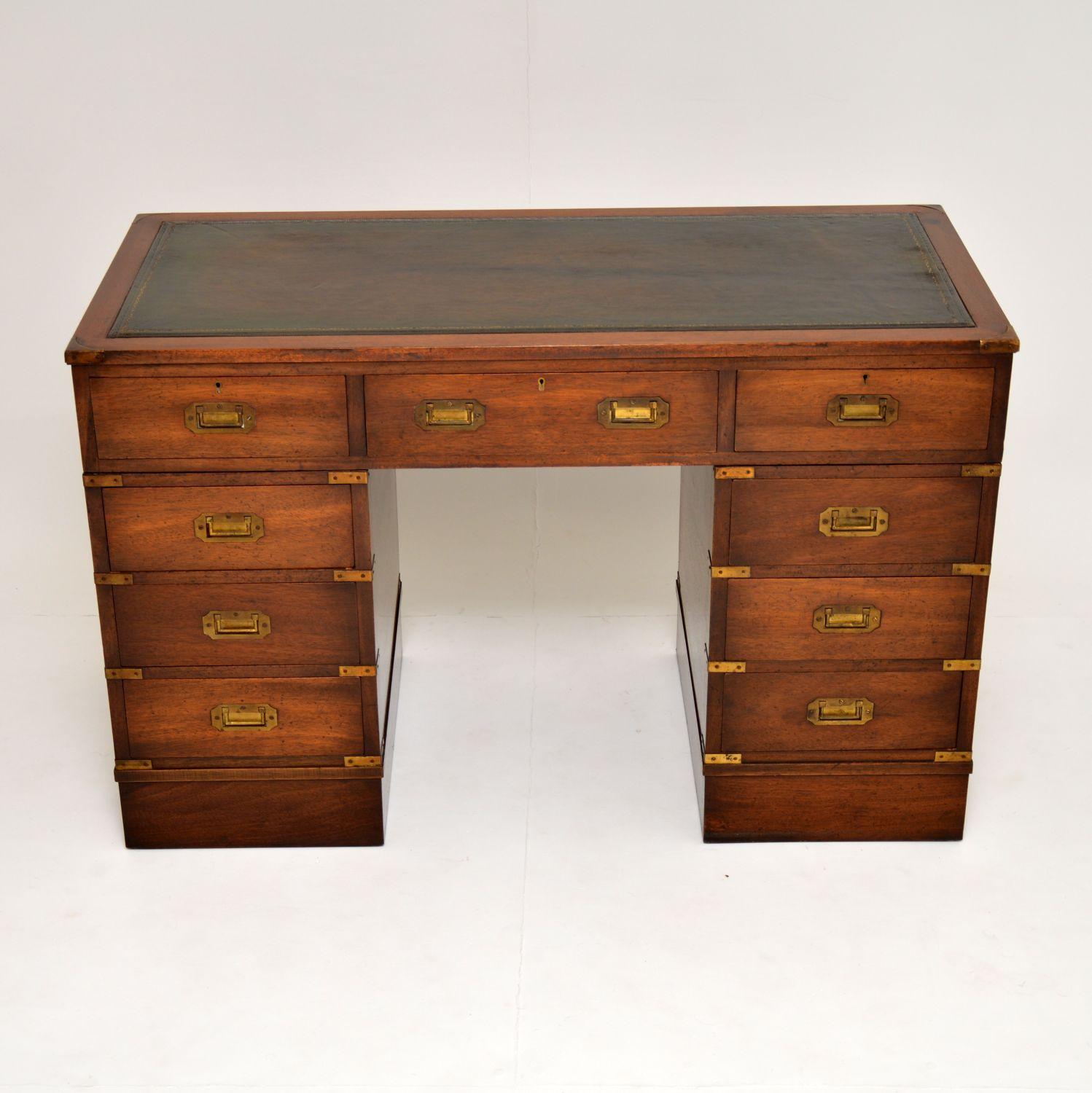 Antique Campaign style mahogany pedestal desk in excellent condition and with lots of character.

It has a tooled leather writing surface, a polished back and sits on bold plinth bases. The drawers have inset brass military handles and there are