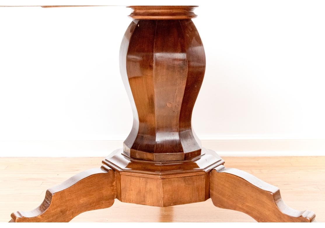 La table est dotée d'une colonne à section décorative surmontant une base octogonale à trois pieds en forme. Le plateau généreux est doté d'un tablier de quatre pouces et d'un grain fin et régulier. Peut être utilisée comme table centrale ou table