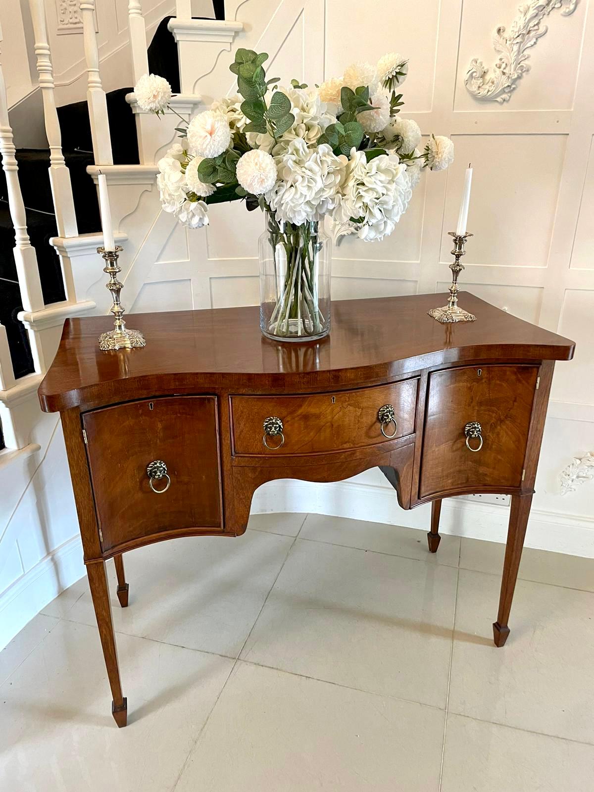 Antique mahogany serpentine shaped sideboard having a quality mahogany serpentine shaped top, bow fronted door to the centre with original brass lions head handles flanked by two serpentine shaped doors with original brass lions head handles, shaped