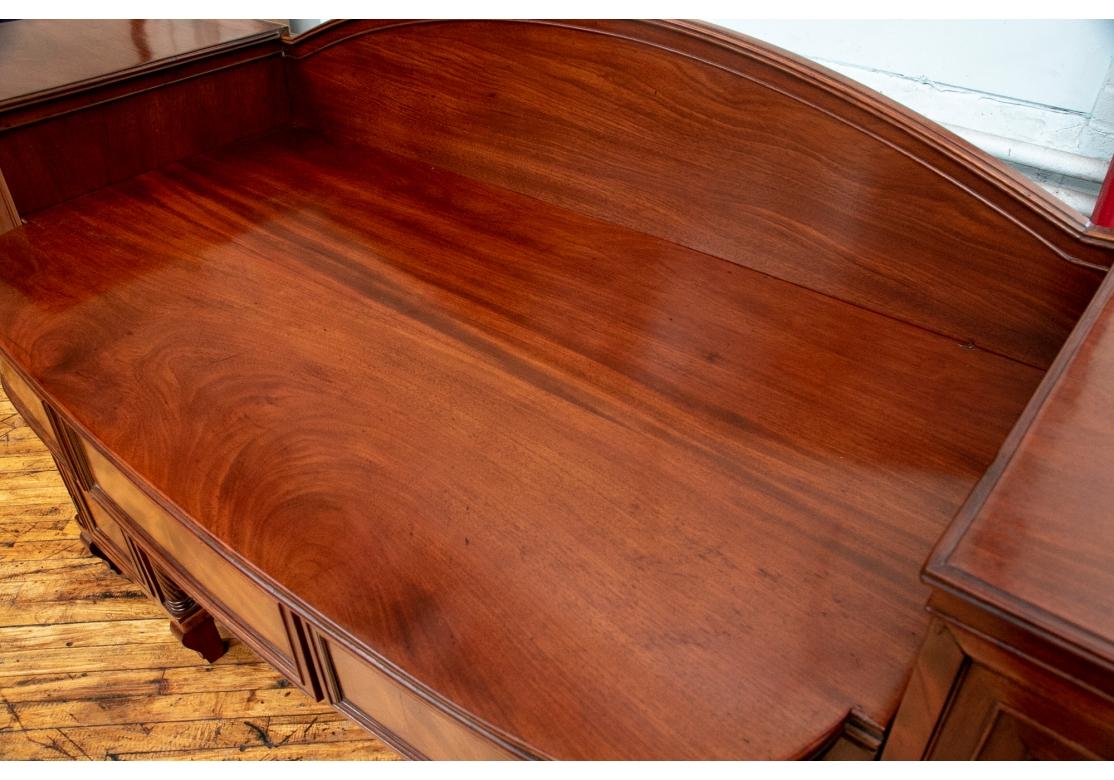 A very well made Antique Sideboard with unusual form and fine presentation. The case with a pair of pedestals linked by an arch shaped back splash in the center. With burled and banded front panels and carved edges. The shaped center apron with