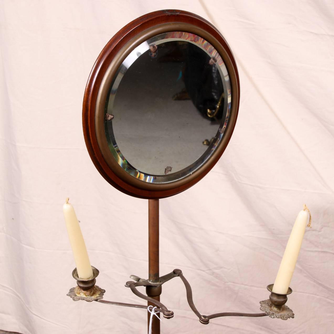 Antique shaving stand with mirror, mahogany round table with attached and adjustable metal support for the circular bevelled adjustable mirror mounted in mahogany, two attached adjustable metal candle arms with floral decorated metal bobeches, lower