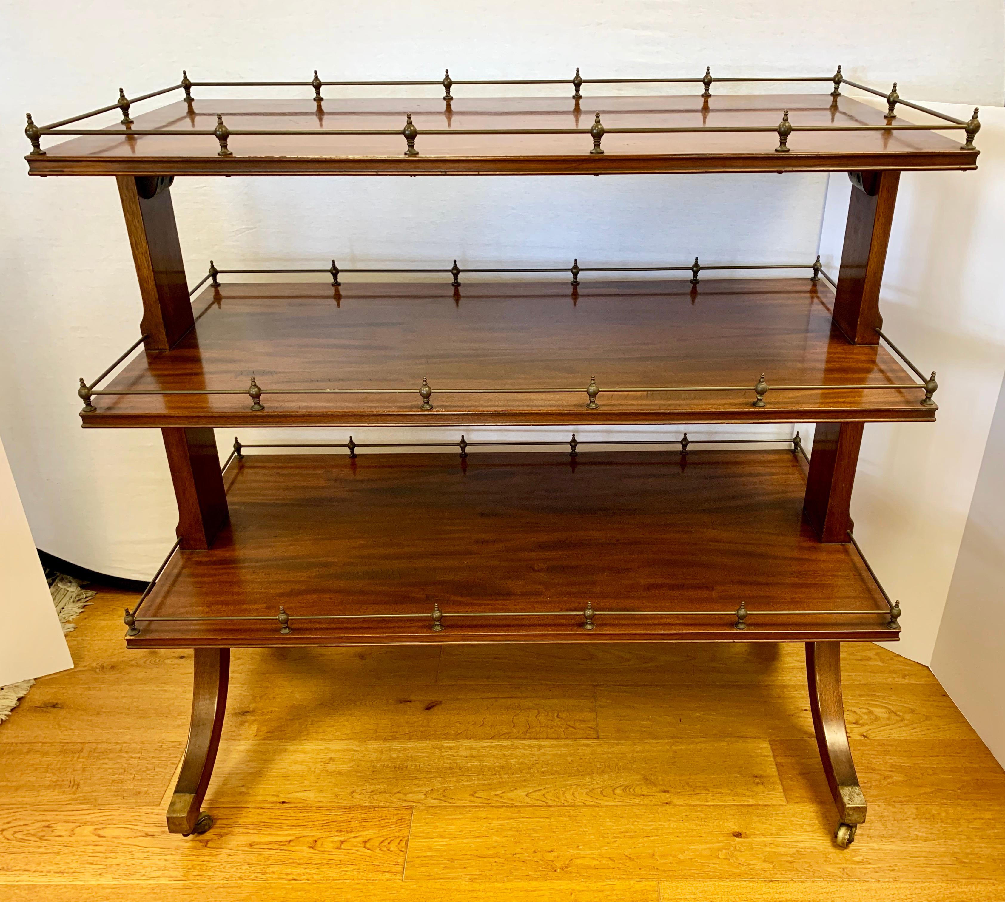 Antique three-tiered mahogany trolley is perfect for serving tea, dessert or drinks. Features a brass gallery all around each shelf and beautiful flame mahogany. On brass castors for ease of movement.