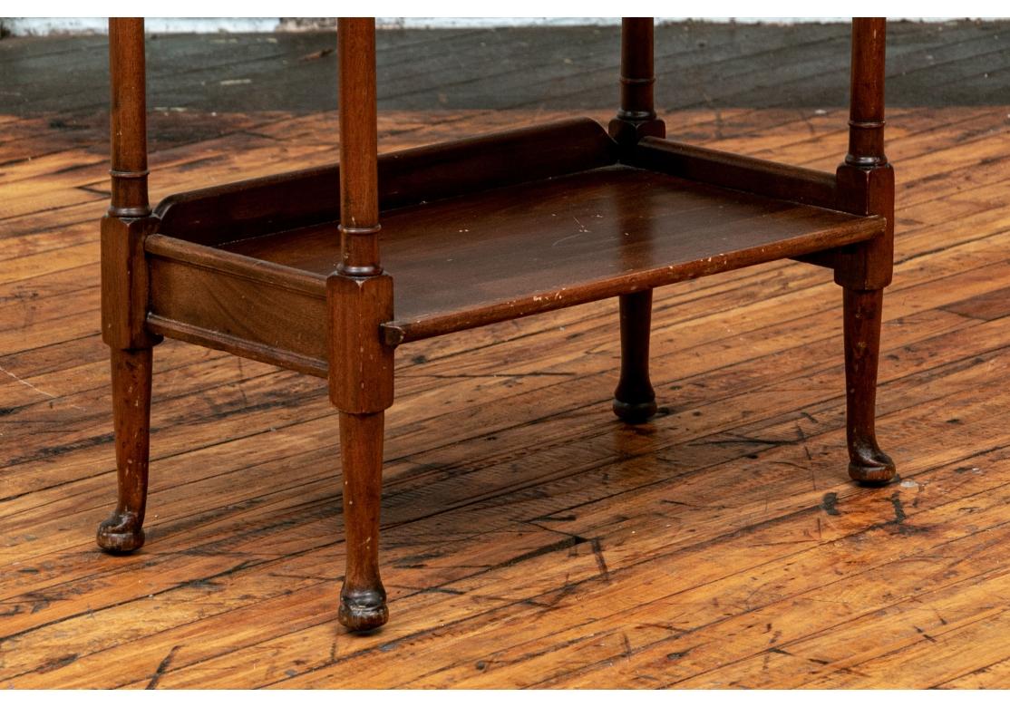 The top with carved edge, the second tier with a divider and 3/4 gallery, and the lower tier with the same gallery. With turned supports and raised on curved legs with pad feet. There are what are believed to be later wood  support slats. underneath