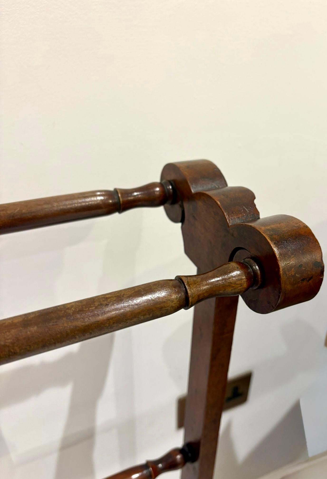 A fine antique mahogany towel rail of elegant proportion featuring three turned hanging bars supported by shaped uprights with carved scroll and shell motifs to the top. The splayed feet are neatly shaped and well-balanced offering both stability