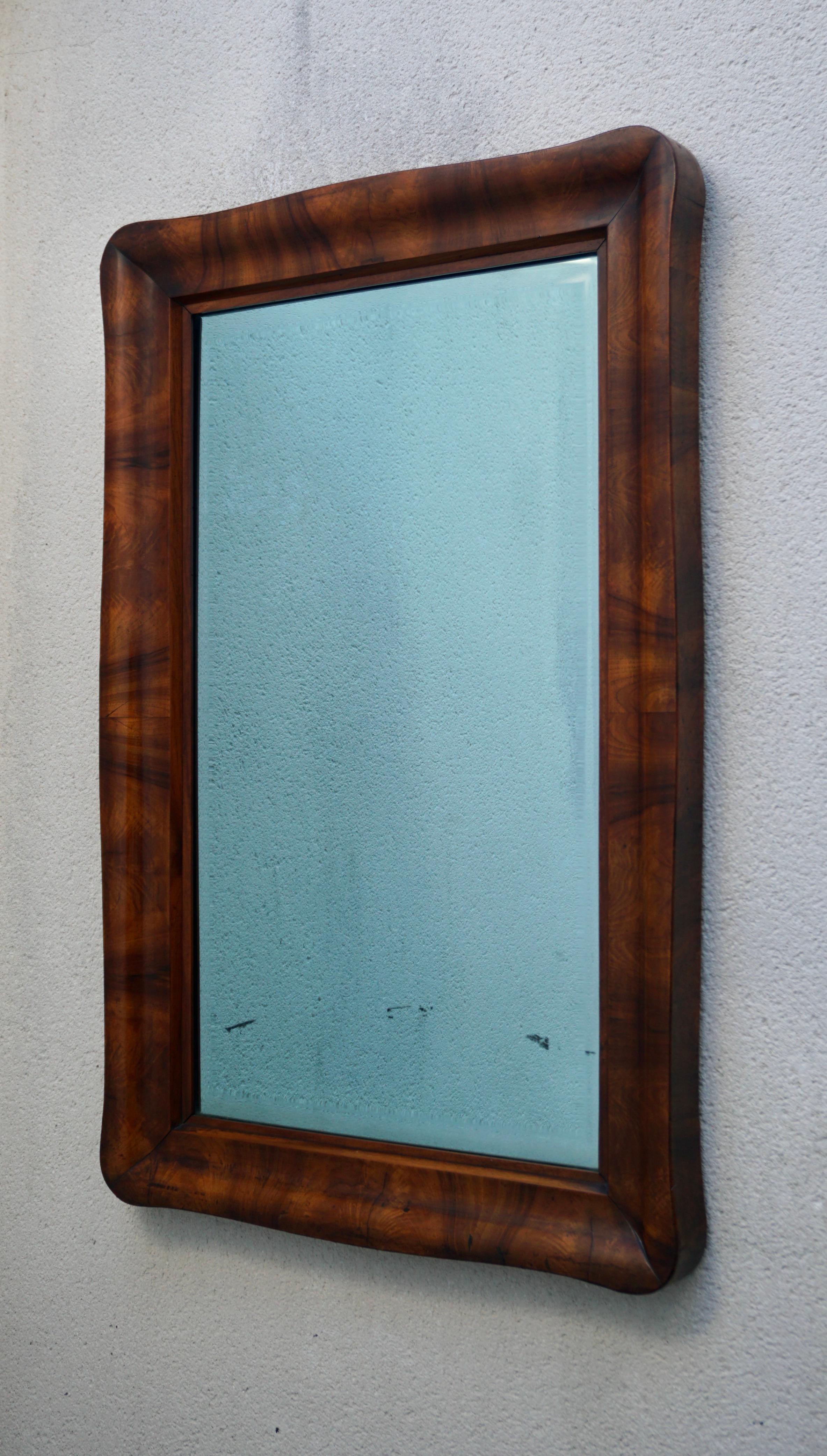 A mahogany veneer 19th century mirror (102 x 66 cm) with old glass.