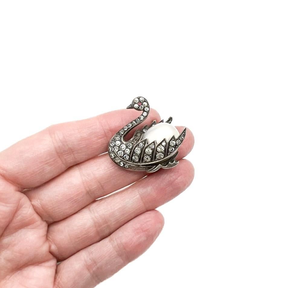 An antique Vintage Swan Pearl brooch most likely made in the late Victorian/early Edwardian era. A majestic swan crafted in solid sterling silver and set with paste chatons. A large, opulent, blown glass pearl emulating the body. An everlasting