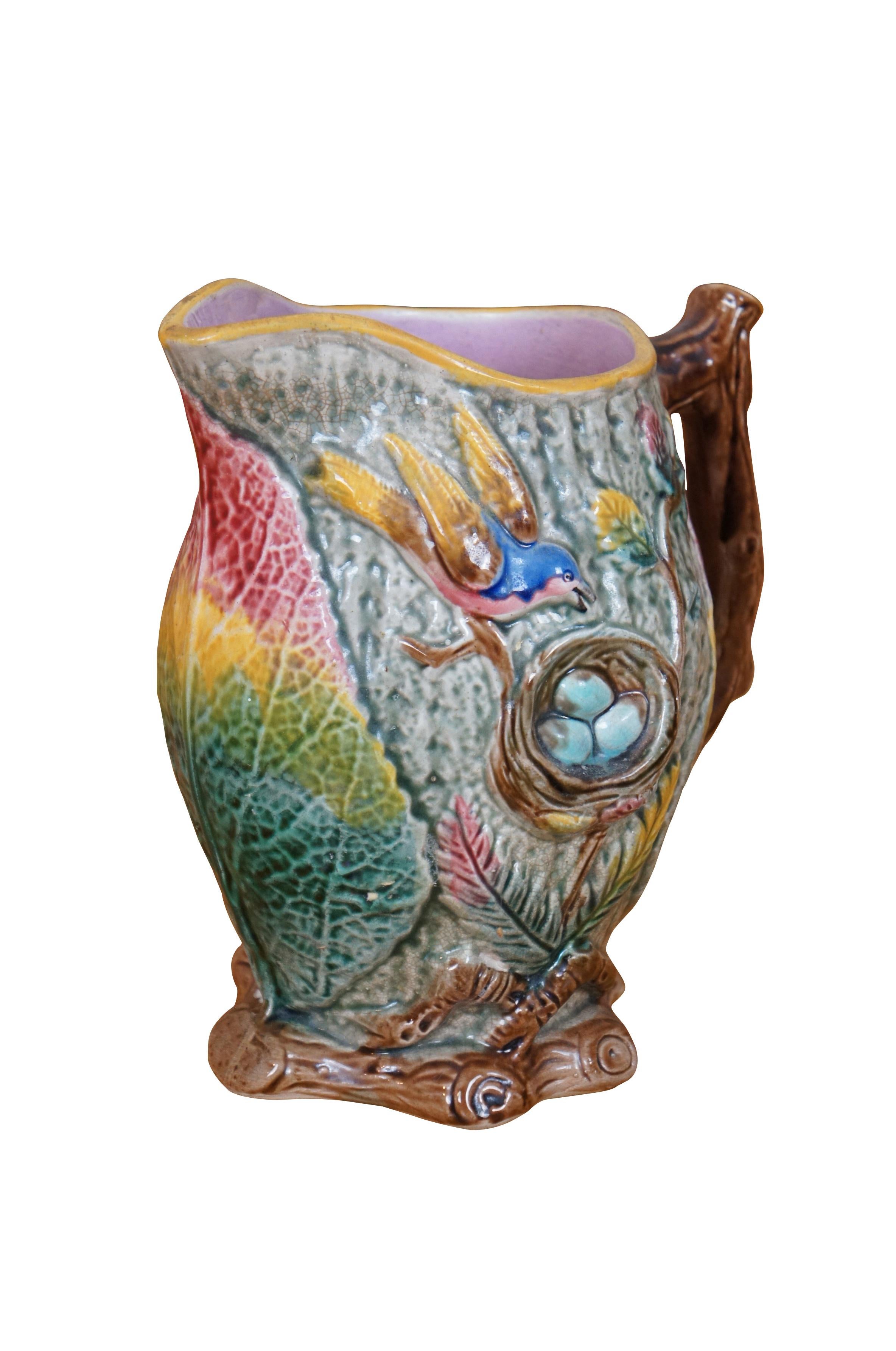 Antique Majolica nesting bird / Robins egg pitcher / creamer / jug attributed to Arsenal Pottery after Shorter & Boulton.  It features a very colorful motif of Begonia leaves and twigs with a tree branch handle and purple lavender interior.  Circa