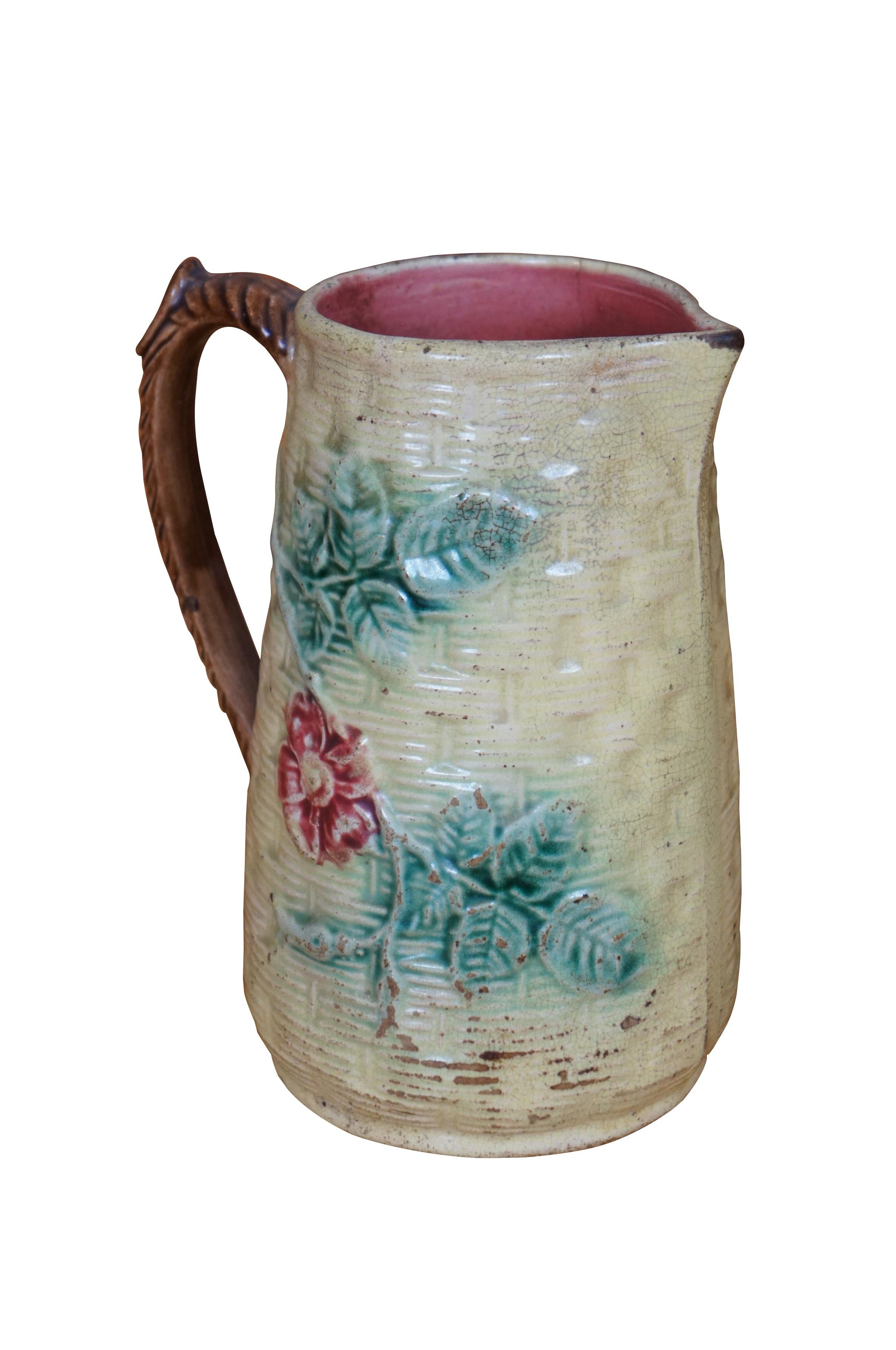 Antique Majolica creamer pitcher or jug featuring a basketweave pattern with bas relief dogwood flower, brown twisted handle with thumb rest.

Dimensions:
5.5