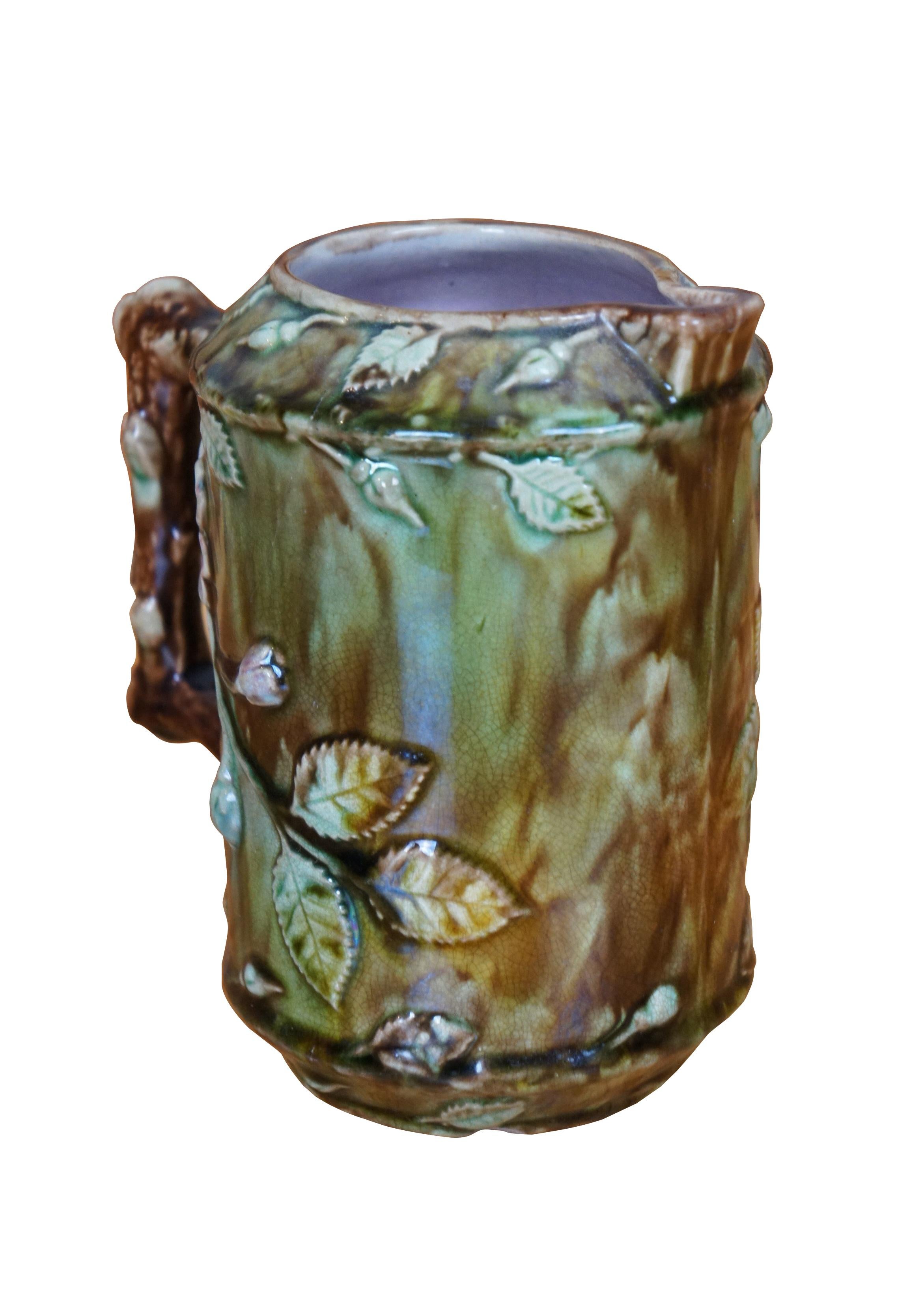 Antique Majolica French Barbotine pitcher / jug / carafe featuring a green and brown field with wild dog rose flower blossoms and a twig / branch handle, and purple lavender interior.

Dimensions:
5.5
