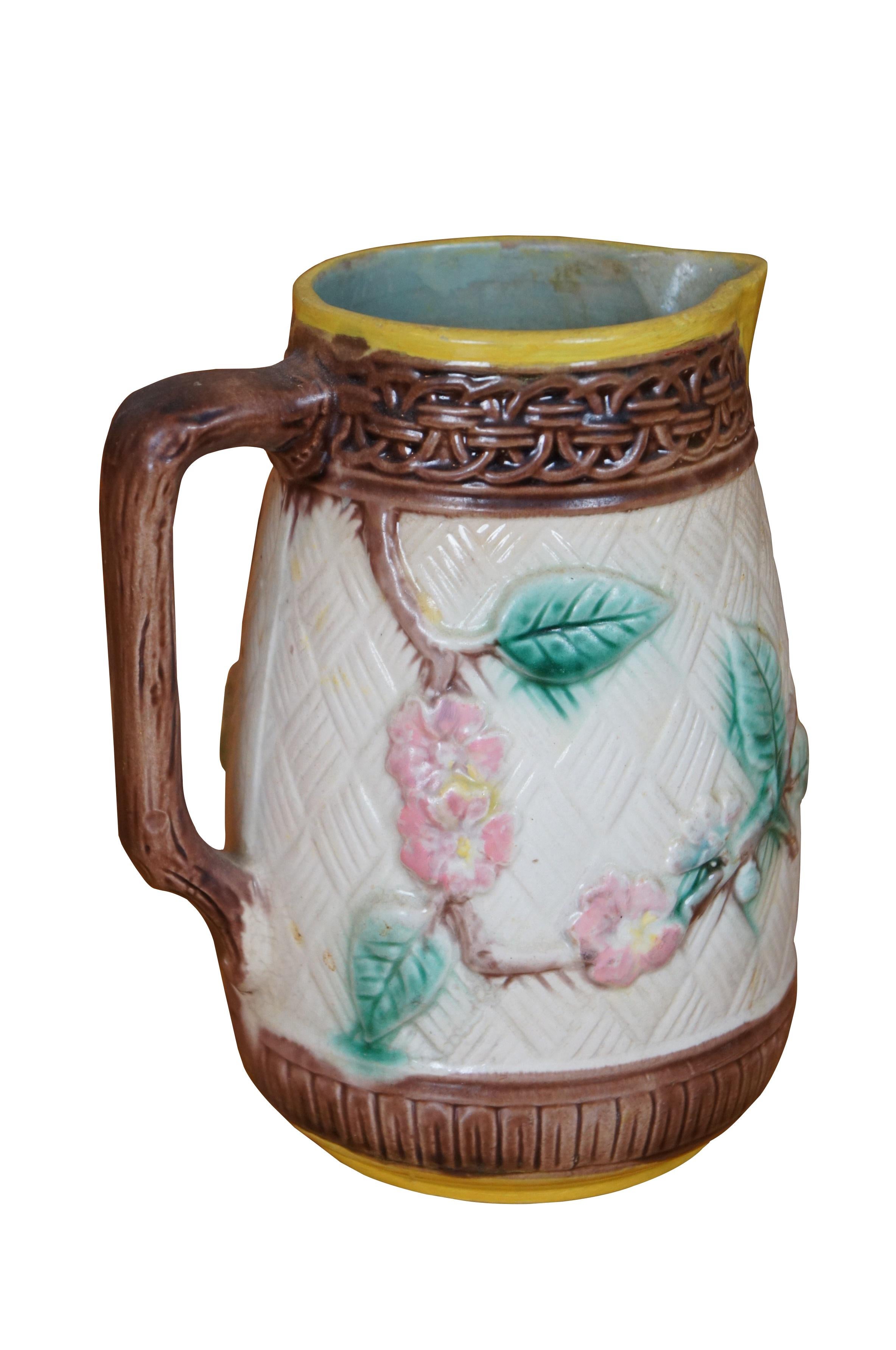 Antique Majolica bas relief parrot / bird / owl / hummingbird and dogwood flower creamer / syrup / honey pitcher or jug featuring a basketweave ground accented with interlocking circles and twig / branch handle.

Dimensions:
6