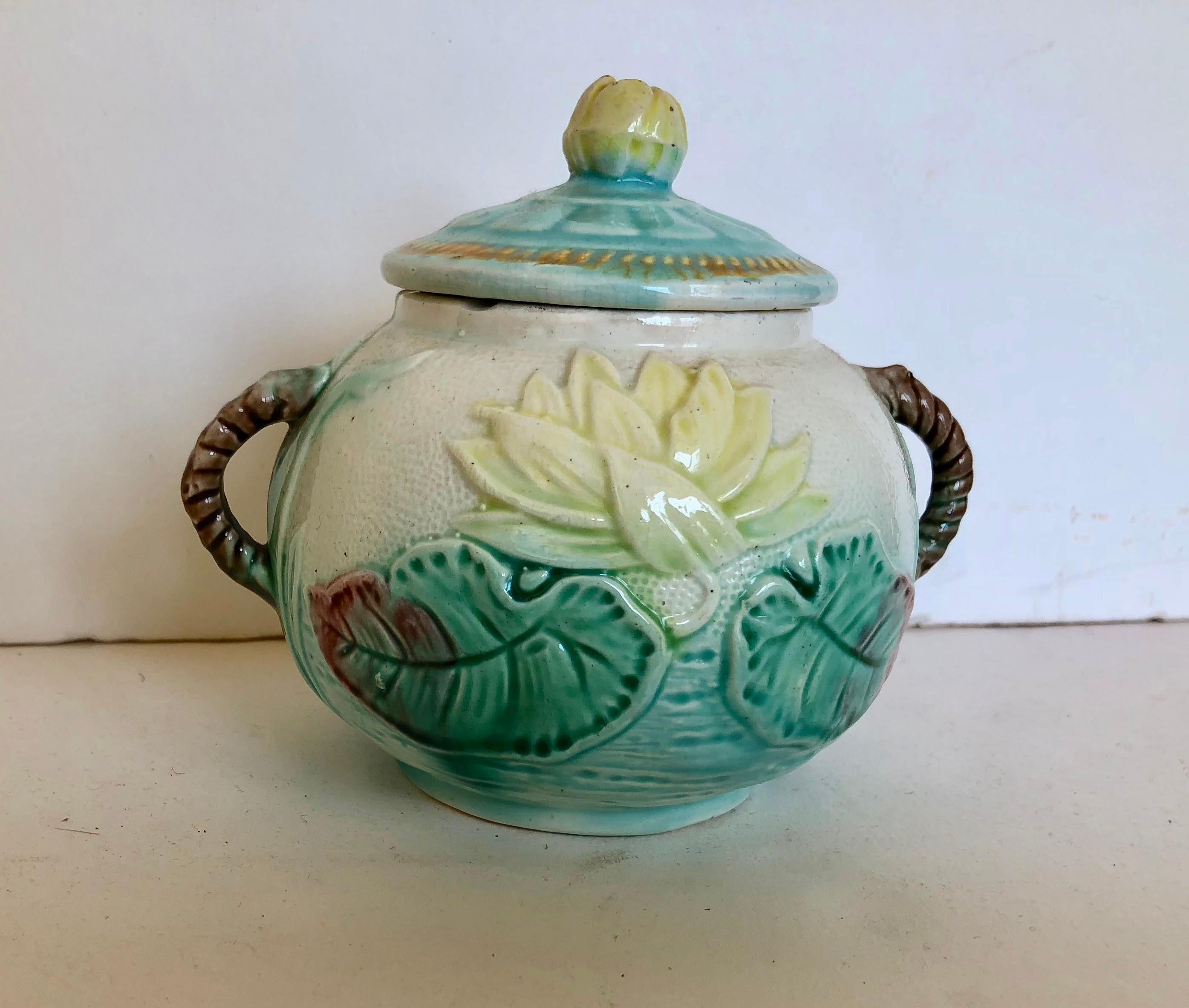 Antique majolica sugar bowl with lid, water lily. Bowl is signed on bottom. Beautiful soft colors and very good condition. A small chip on rim of bowl under lid and some crazing, commonly found in a piece of this age. A very nice piece of Folk Art.