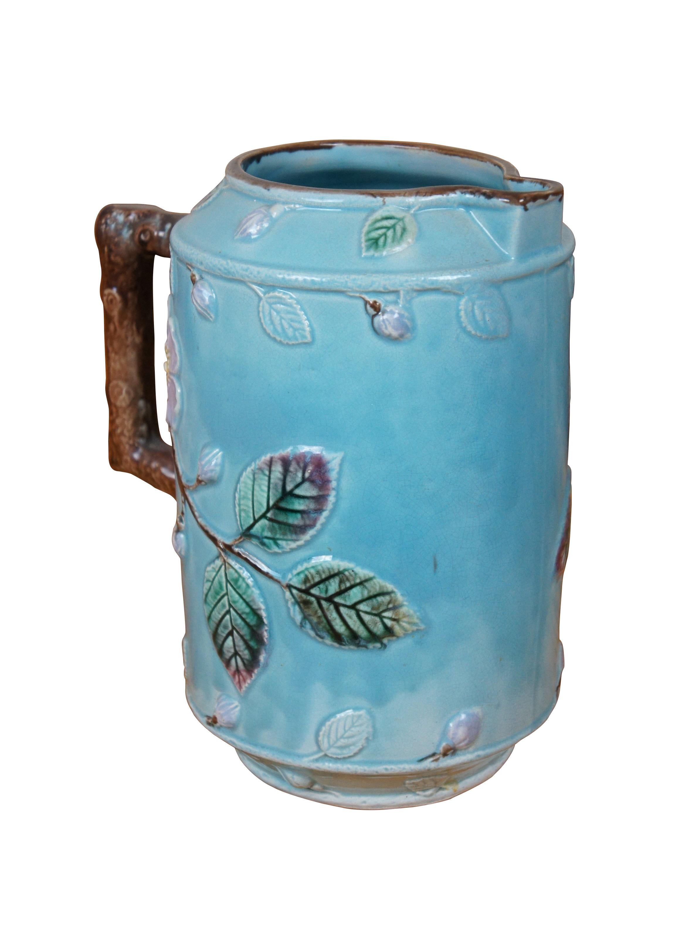 Un très grand et impressionnant pichet / cruche / carafe antique en majolique française, présentant un champ bleu turquoise avec des fleurs d'églantier violet lavande et une poignée en forme de brindille / branche.

Dimensions :
8