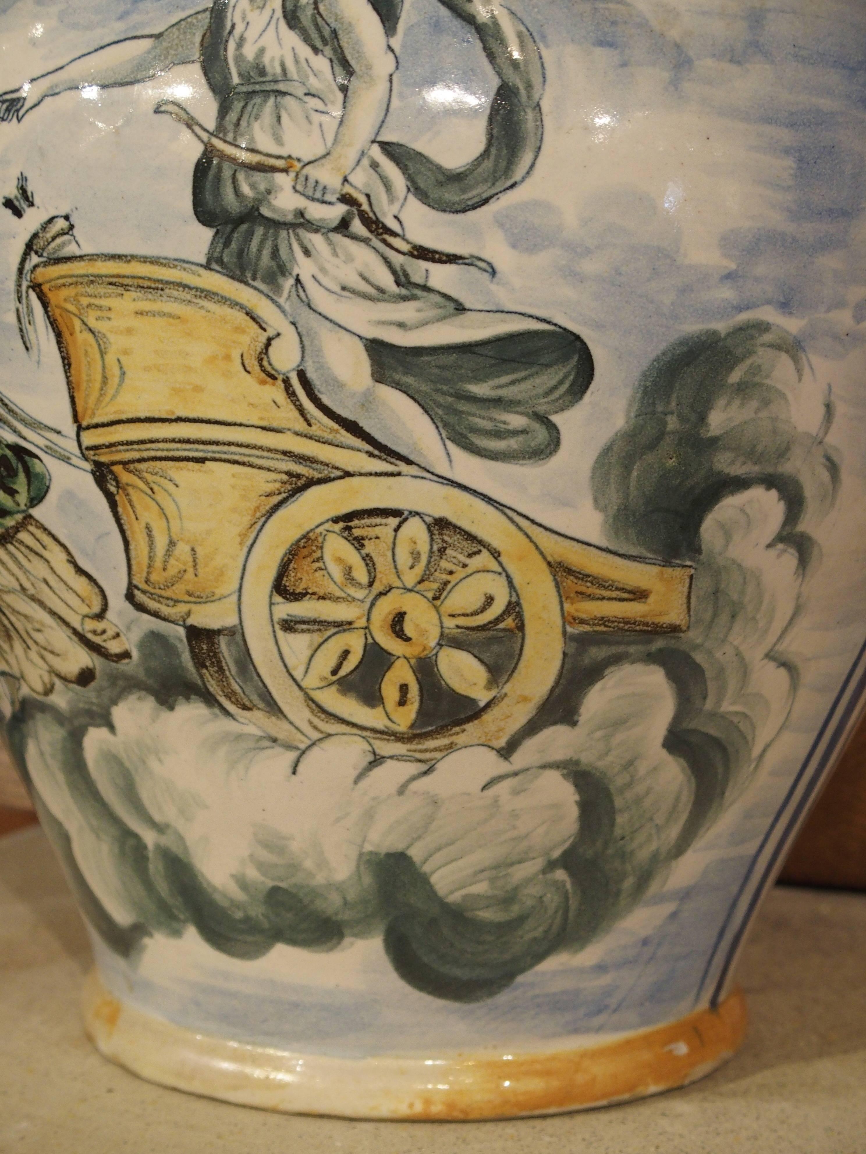 From Italy, this stunning antique Majolica urn depicts a mythological scene on one side and a large workshop marking and date on the other. The mythological scene depicts a young man in a chariot that is being pulled by two maidens in stylized