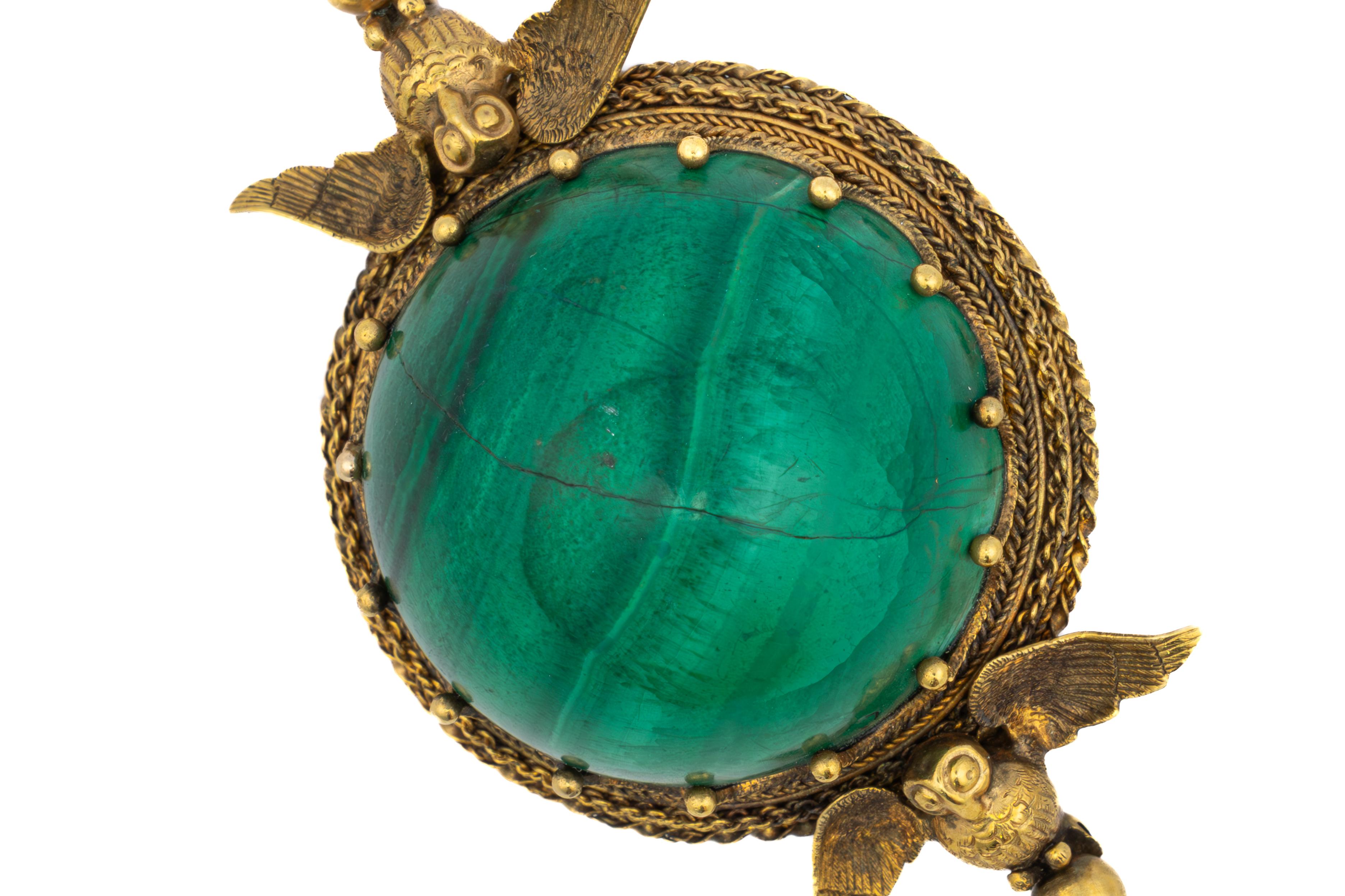 Antike Brosche mit Malachit- und Eulenmotiv

Beschreibung:
Diese antike Brosche zeigt einen reich gebänderten grünen Malachit-Cabochon, der in einen Rahmen aus strukturiertem 14-karätigem Gelbgold eingefasst ist. Oben und unten scheinen fein