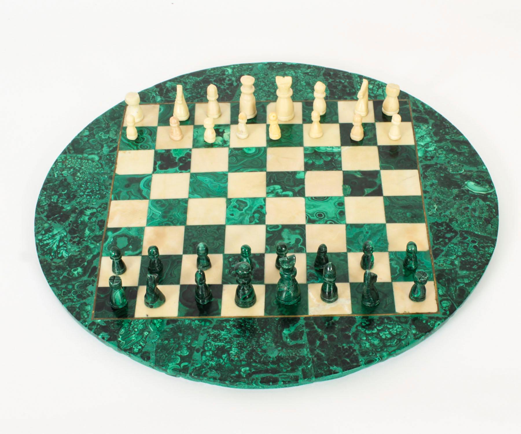 Voici un magnifique jeu d'échecs italien ancien en malachite et marbre de Carrare datant d'environ 1920.

L'échiquier en malachite est de forme circulaire et est entouré d'un cordon en laiton incrusté. Il est accompagné de pièces d'échecs en