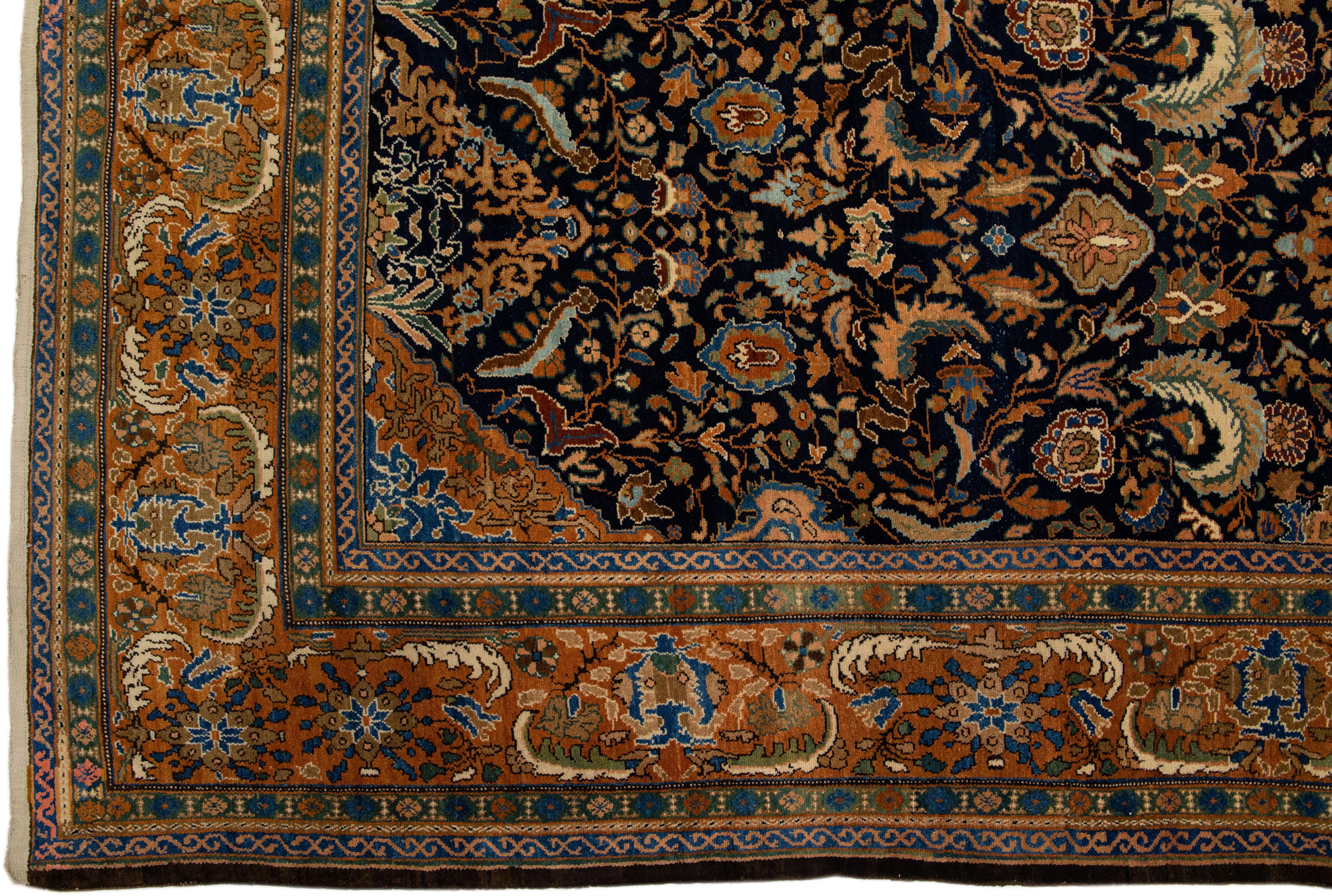 Beautiful antique Malayer hand-knotted wool rug with a navy blue field. This Persian piece has blue and orange rust accents in an all-over floral design. 

This rug measures: 12'6