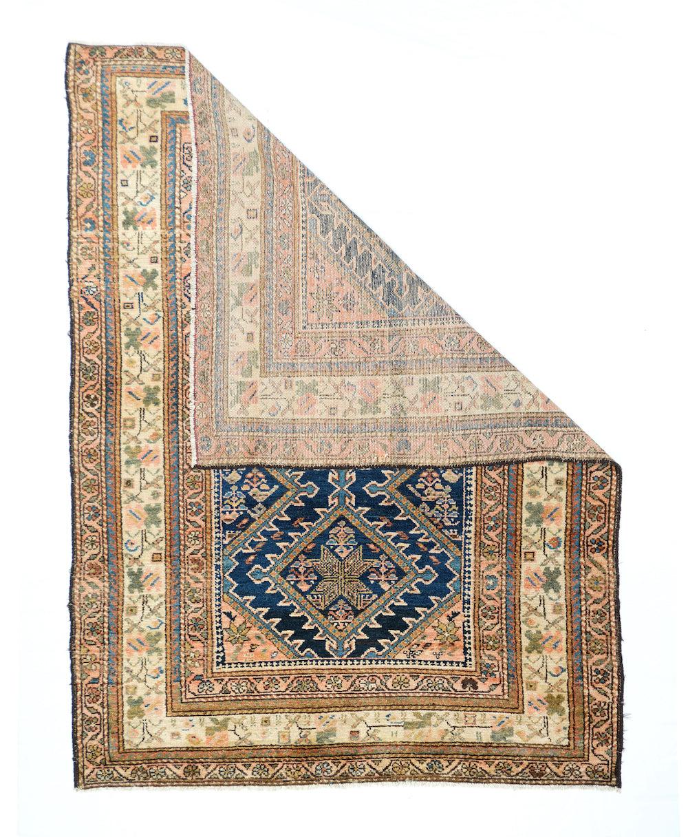 Alfombra Malayer Antigua 4'7'' x 6'5''. El sistema de bordes, centrado en una franja crema con flores de tallo, tiene una tonalidad clara que contrasta con un rico campo azul real que muestra los medallones de diamantes fuertemente barrados que