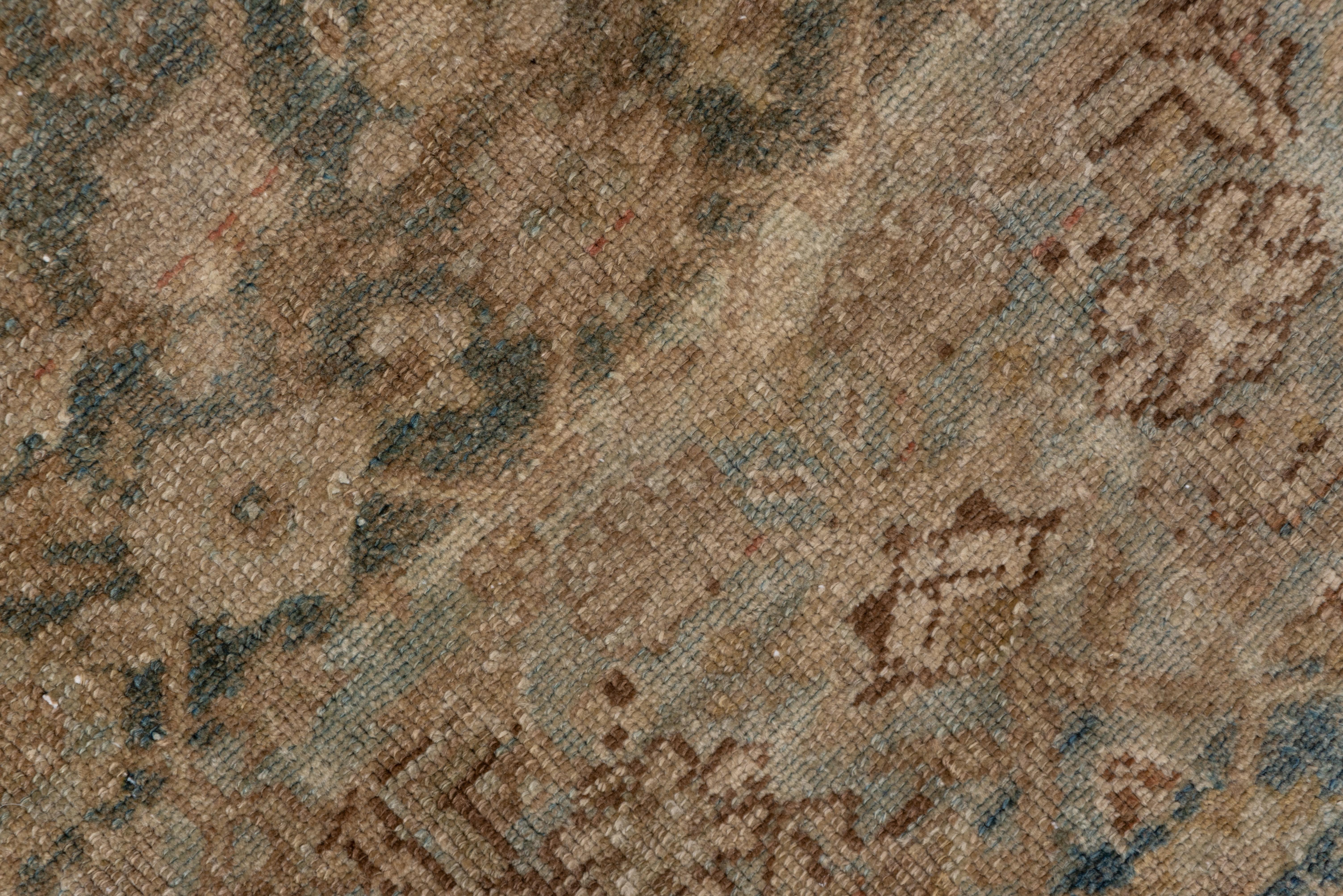 This essentially earth-toned west Persian rural scatter shows a color-reduced Herati pattern on a strongly abrashed brown ground, set within a wide beige border decorated with an angular vine sprouting progressive flowers in the Mahal style.