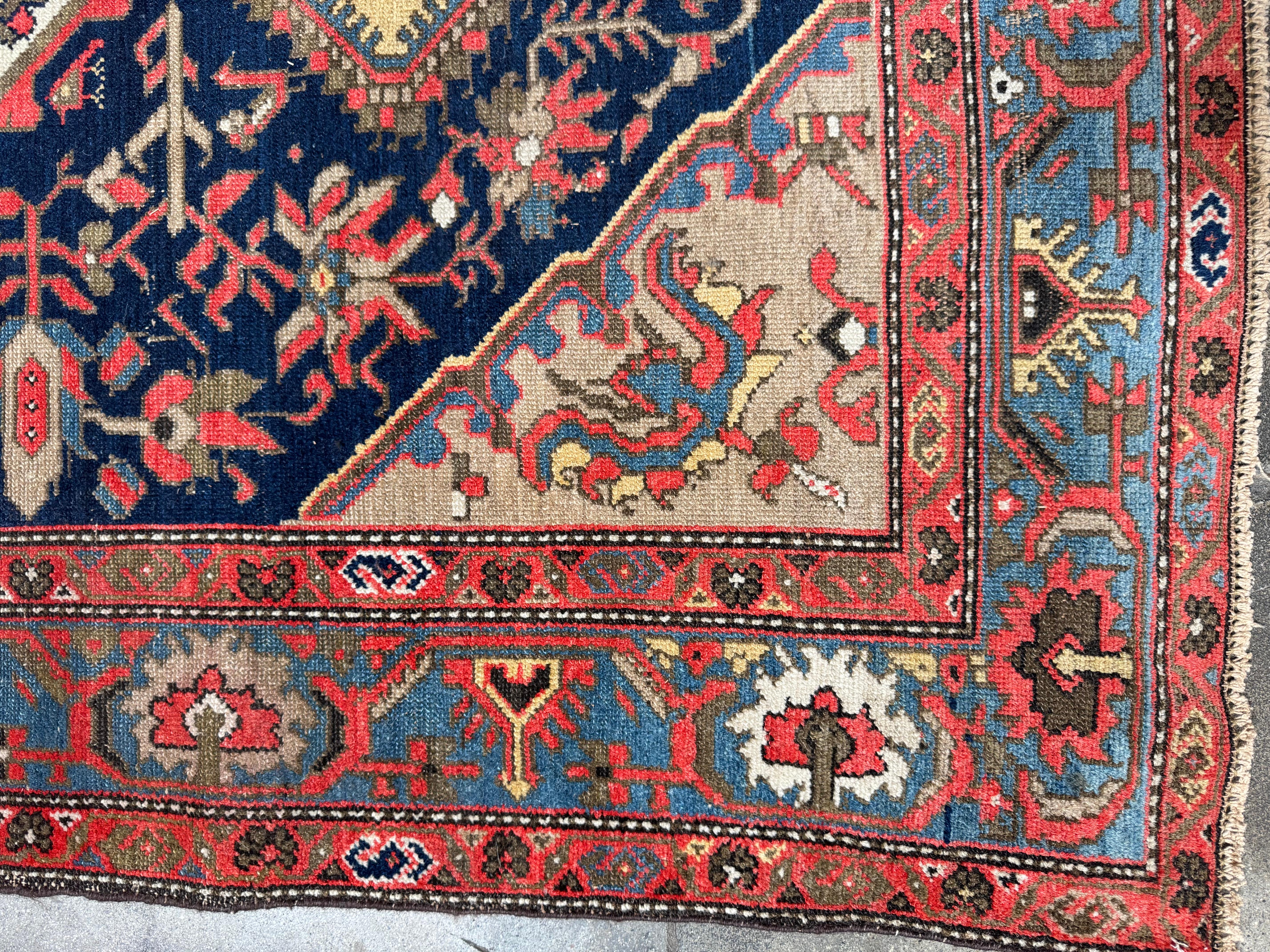 Ce tapis ancien de Malayer présente une riche tapisserie visuelle avec un médaillon central bleu marine profond flanqué de motifs floraux et de vignes complexes dans des tons doux d'ivoire, de terre cuite et d'olive. L'étonnant médaillon est encadré