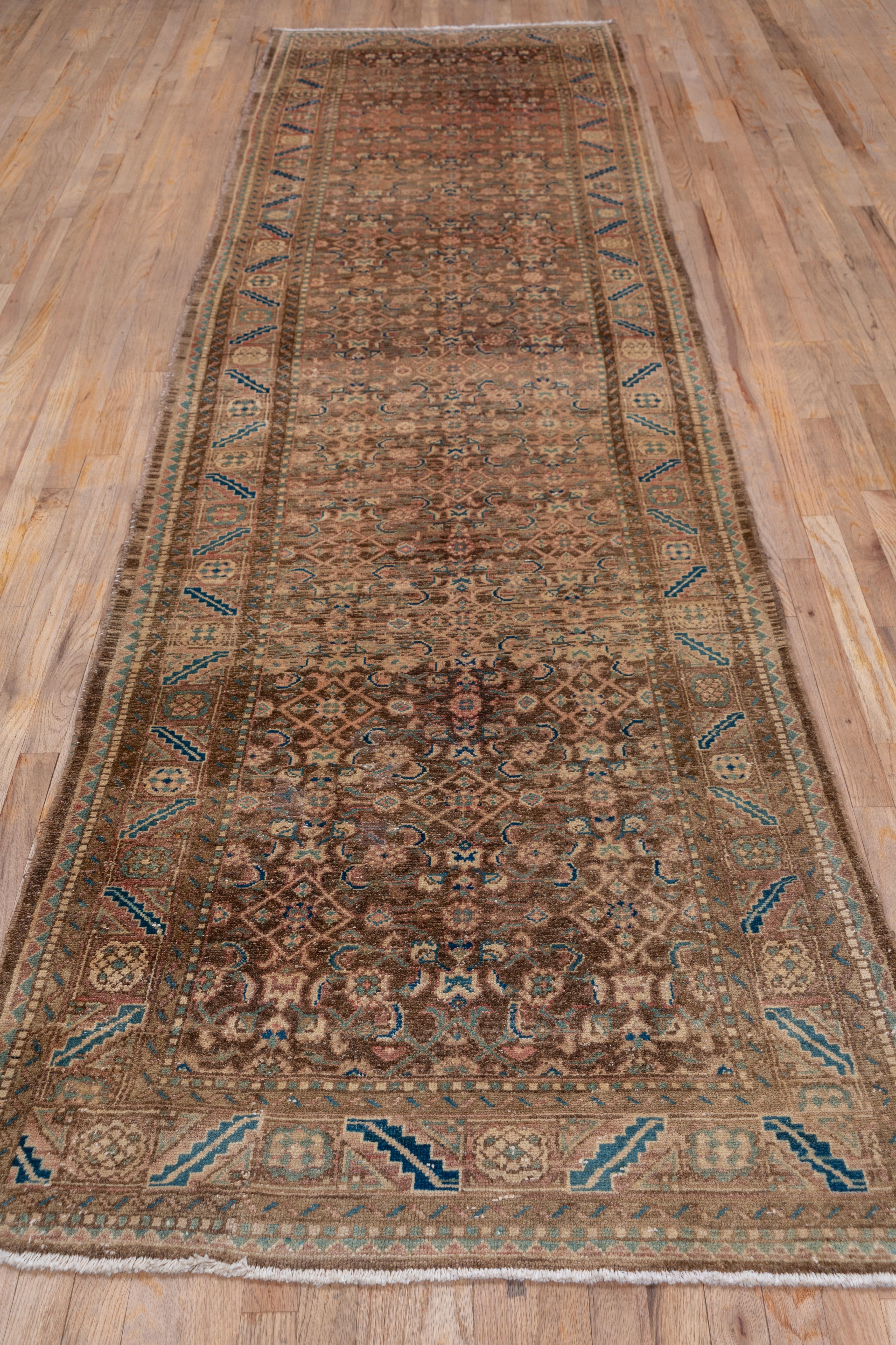 The red-brown ground supports an offset three column Herati pattern detailed in old ivory and dark blue. Teal and dark blue serrated slant leaves flank mosaic pattern rosettes.