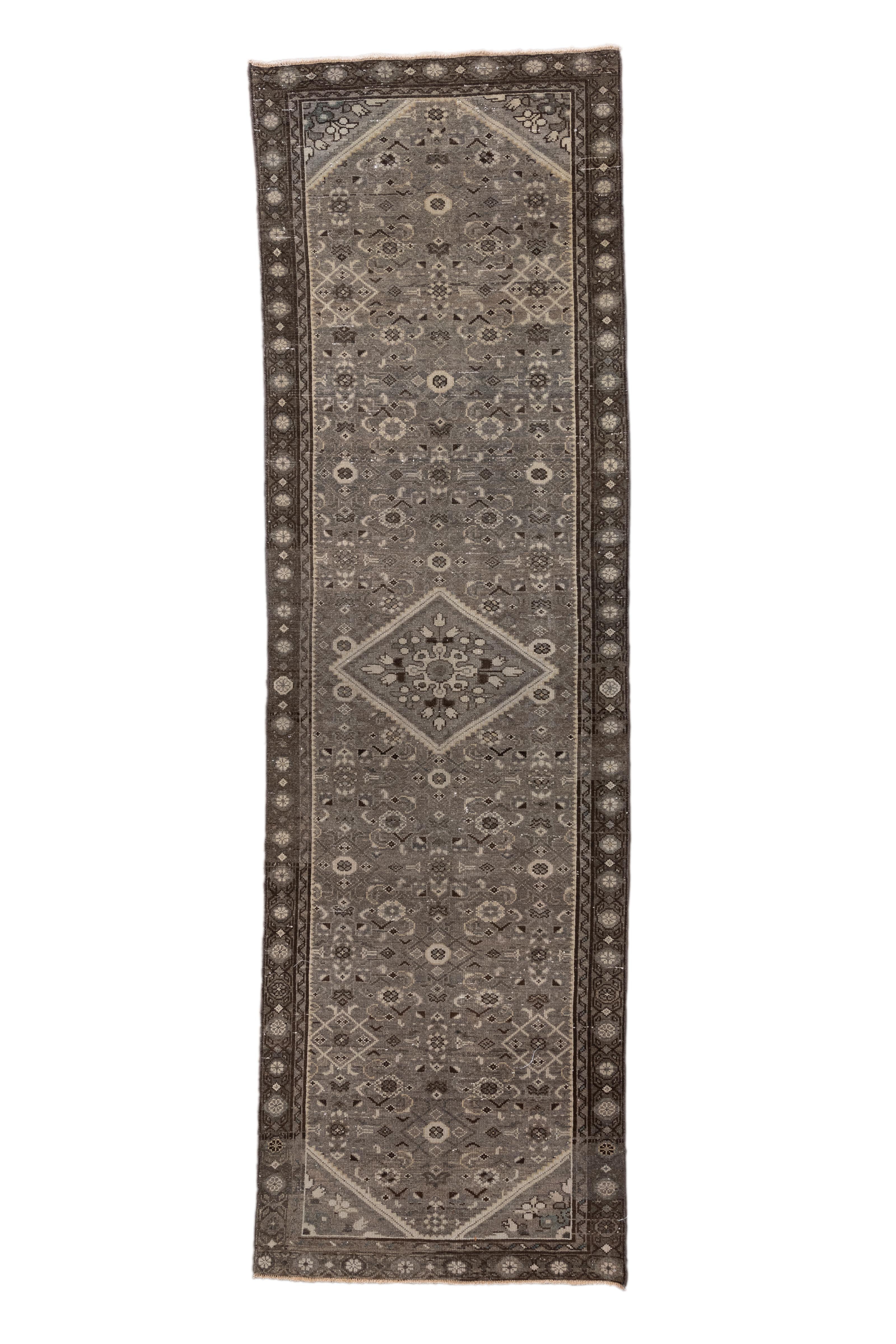 Magnifique chemin de table antique de Malayer, cette pièce présente un motif allover sophistiqué ponctué d'un médaillon central en forme de losange et de subtils écoinçons d'angle. Le champ est richement décoré d'un treillis géométrique répétitif de
