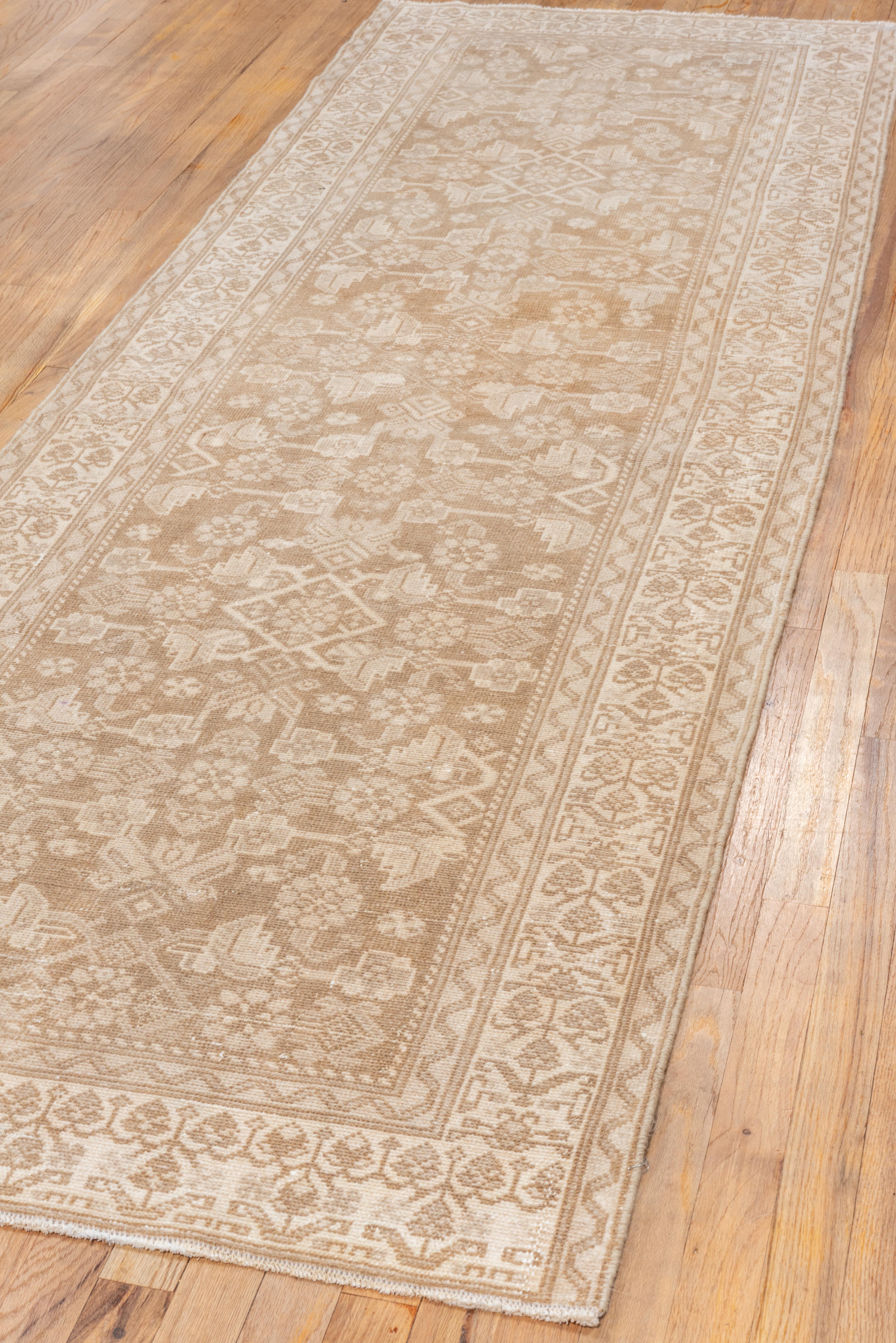 Dieser antike Malayer-Läufer präsentiert mit seiner harmonischen Mischung aus weichen Sand- und Elfenbeintönen eine raffinierte und ruhige Ästhetik. Das mit einem zarten Allover-Gittermuster gewebte Design zeigt stilisierte florale Motive und eckige