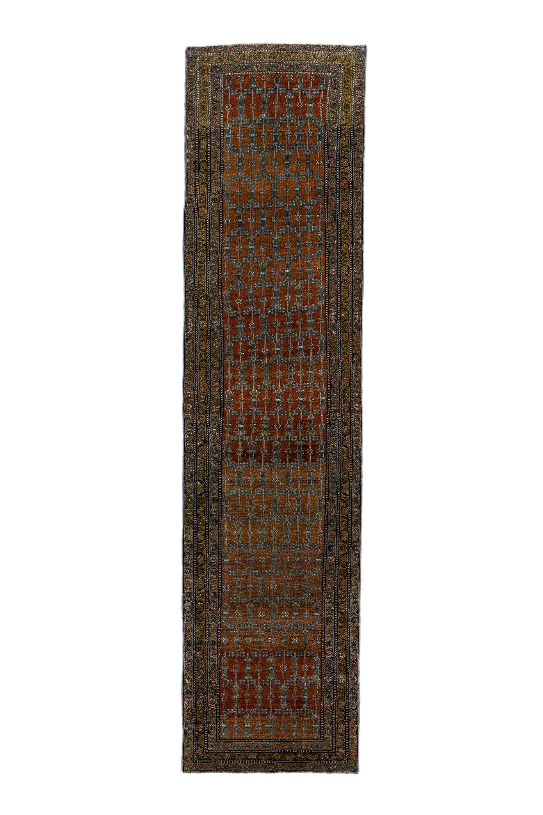 The rust/red/coral panel-abrashed field of this unusual kenare (runner) field  nine parallel vertical rod-like pole with  rosettes and sharp, small lozenges as decorations. The three narrow borders all show identical runs of reversing fan palmettes,