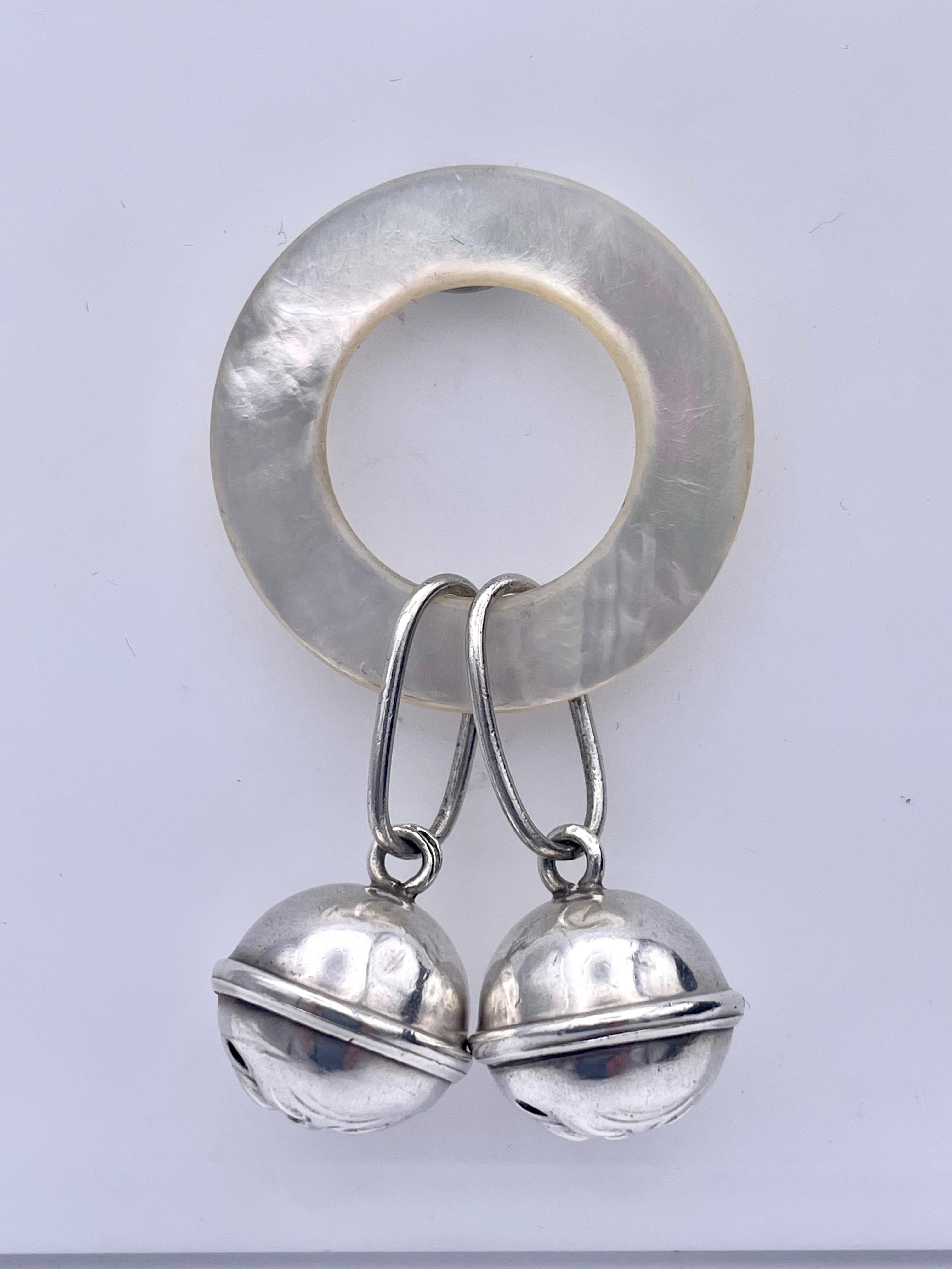 Whimsical baby rattle: two bells with man-in-the-moon faces.  Sterling silver on a mother-of-pearl ring.  American, c. 1890.  For a lucky much loved baby.

Alice Kwartler has sold the finest antique gold and diamond jewelry and silver for over forty