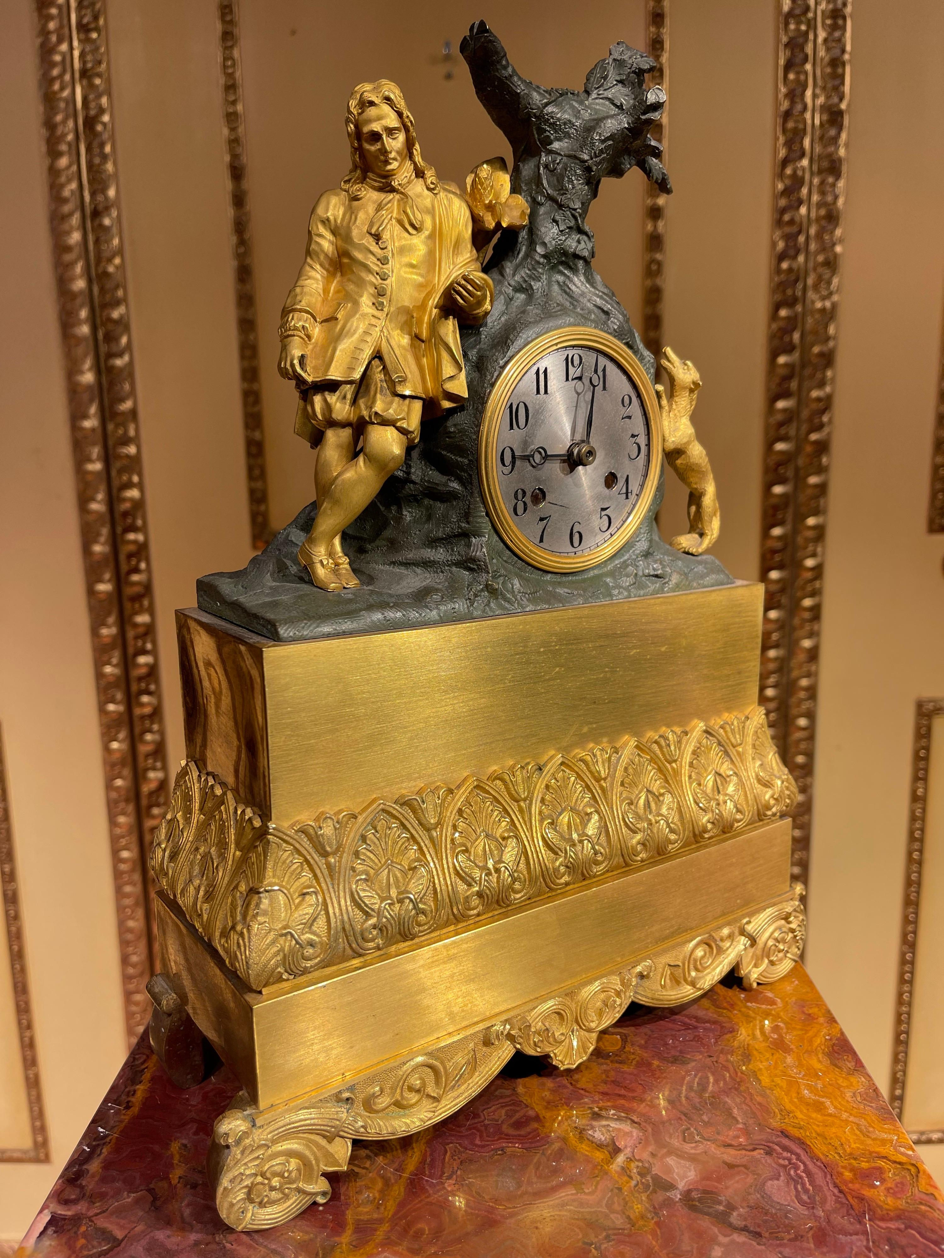 Antique mantel clock from around 1850, France, fire-gilded.

Fire-gilt and partially black-brown patinated bronze. Figurative attachment in the form of a poet leaning against a tree stump as a clock case with a letter in his left hand. Silvered